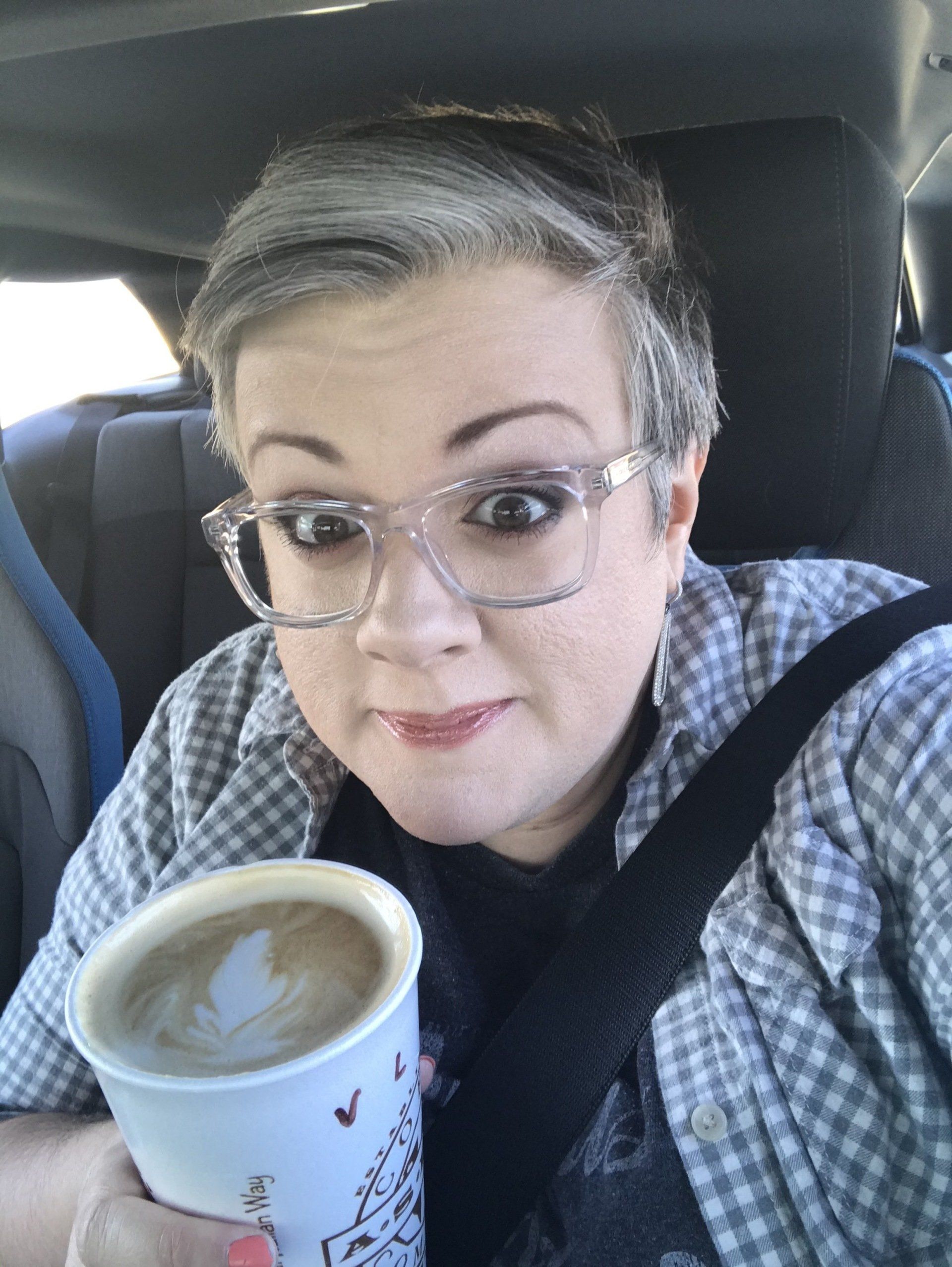 happy woman, aspen coffee, latte art, seat belt, car selfie, clear glasses
