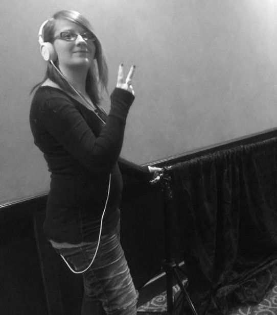 female photographer assistant wearing headphones, hand peace symbol