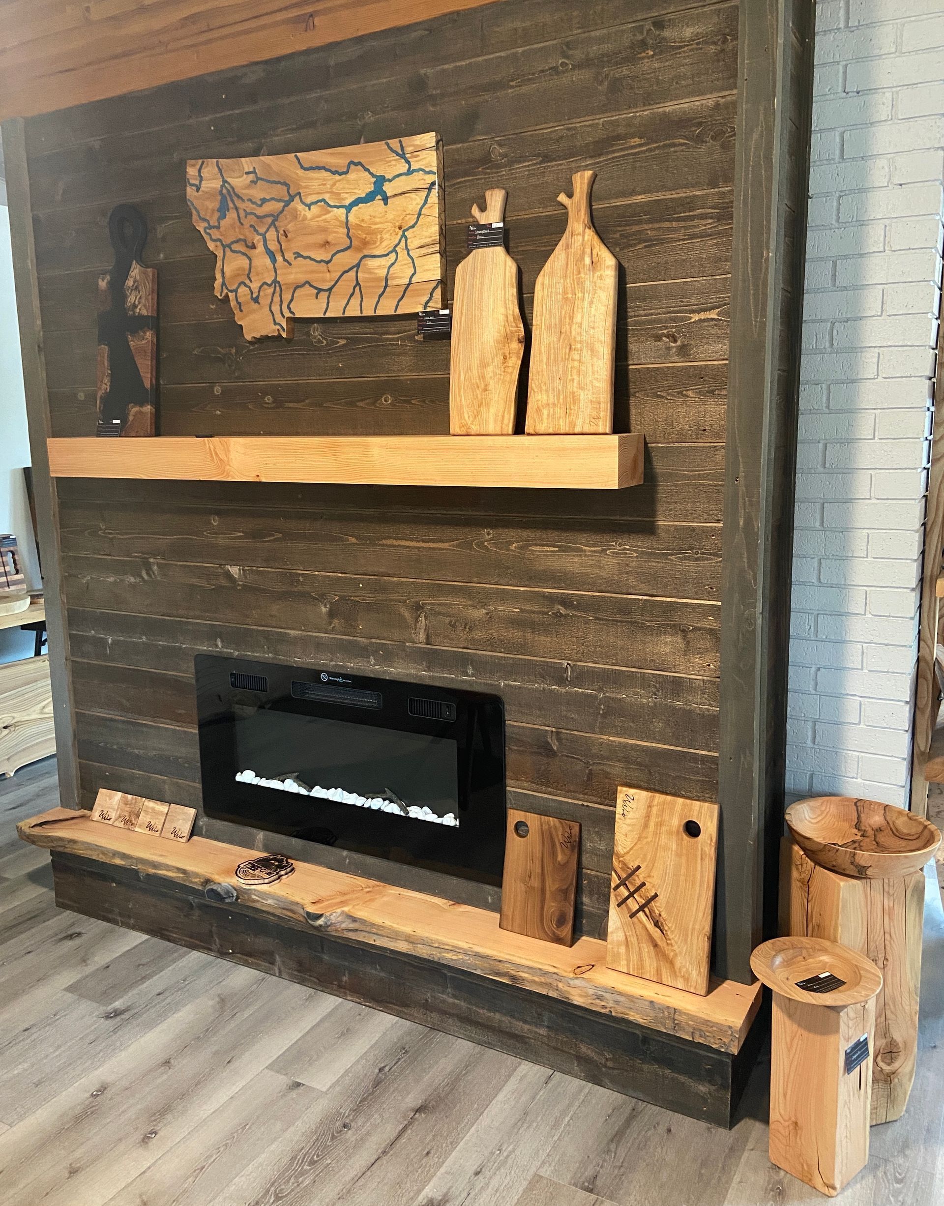 A rustic fireplace with wooden accents and decor, including cutting boards and a Montana map.