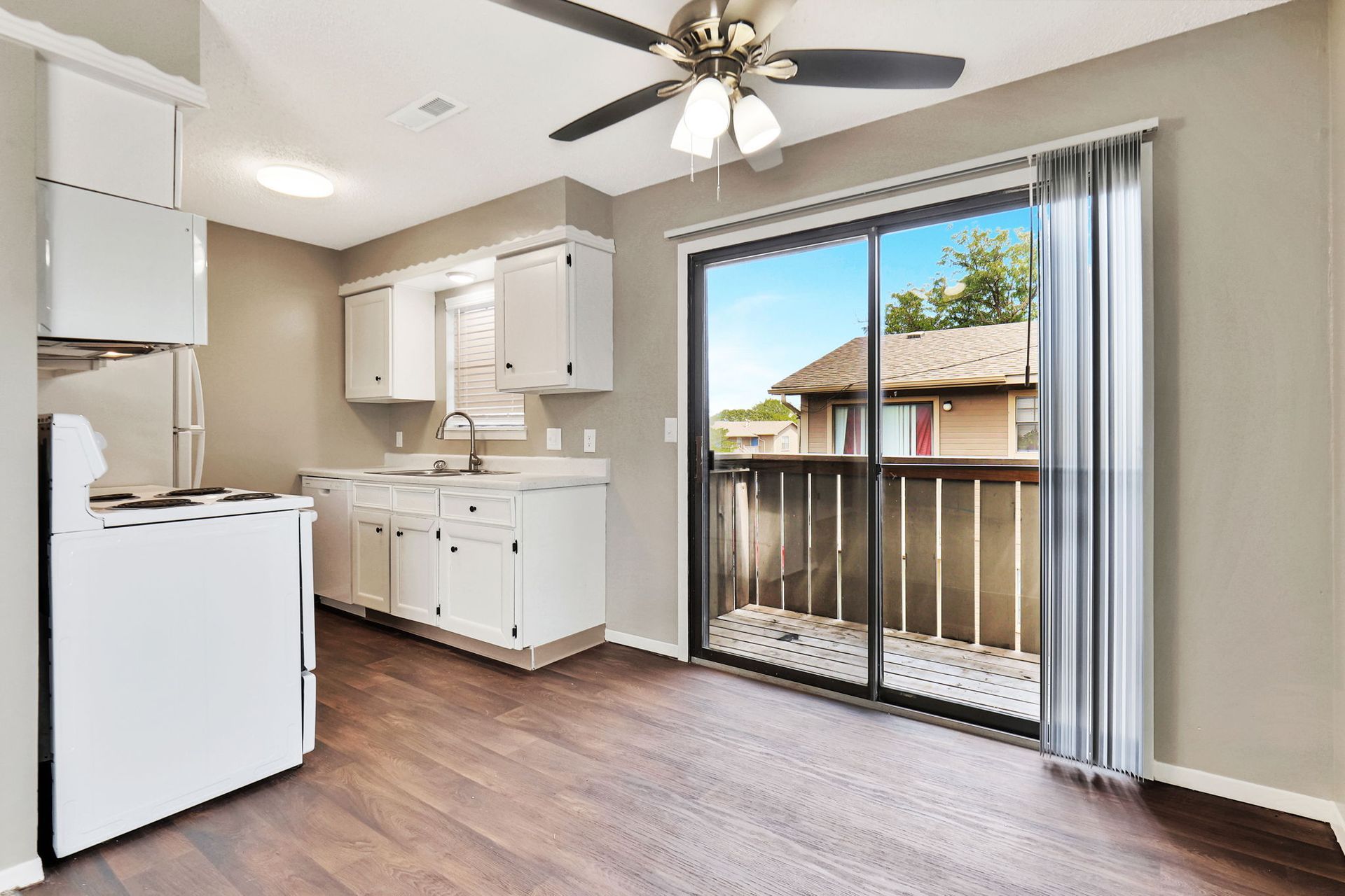 A kitchen with a ceiling fan and sliding glass doors leading to a balcony.