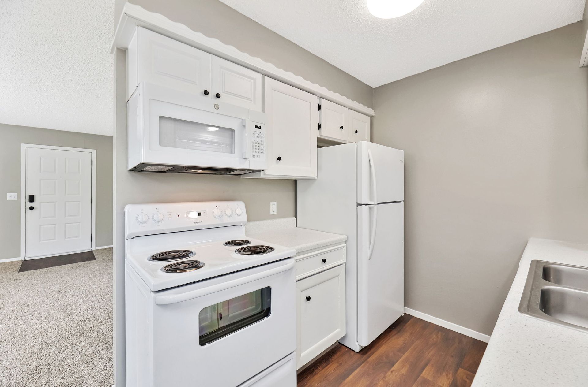 A kitchen with a stove , refrigerator , microwave and sink.