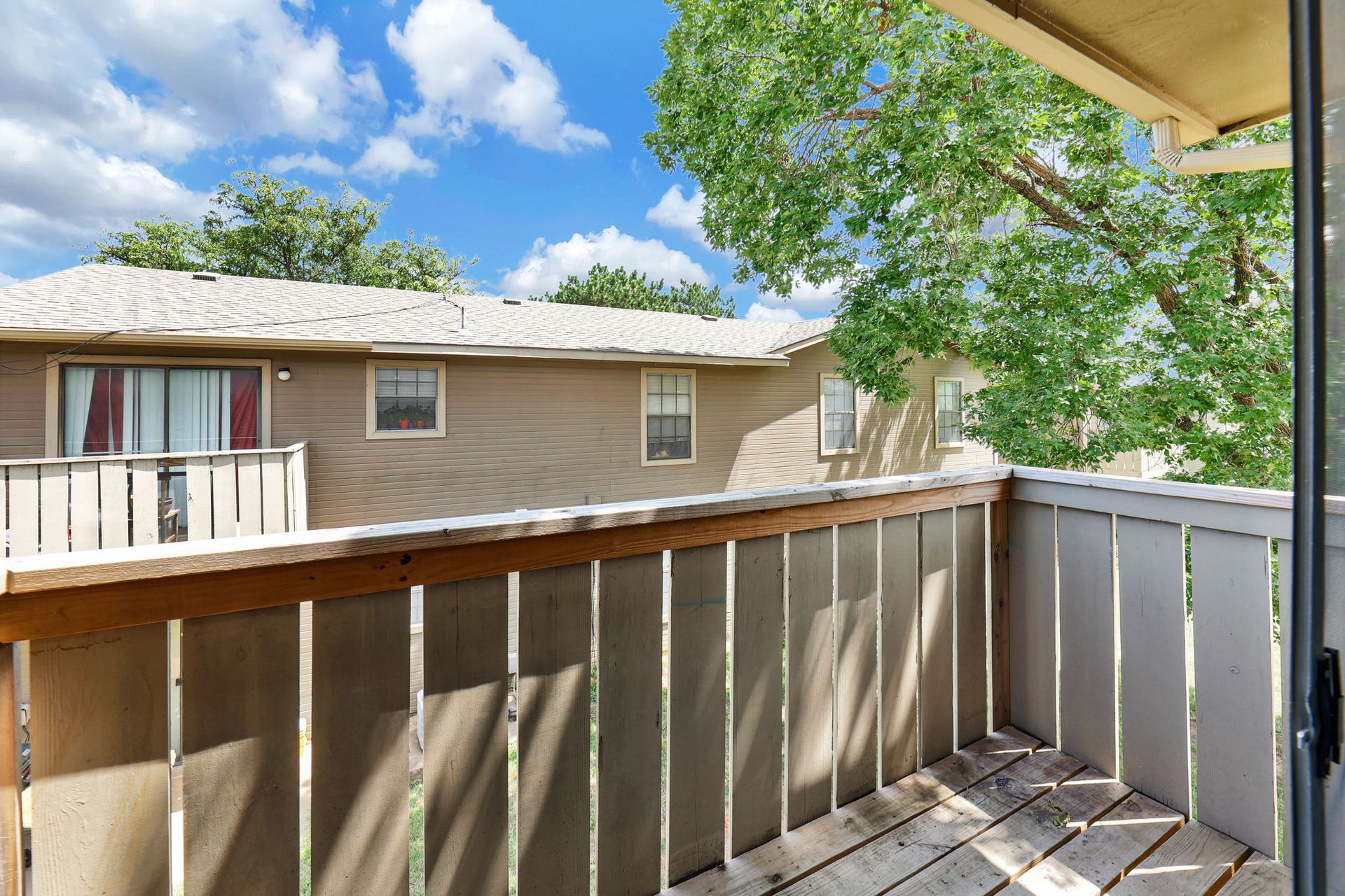 A balcony with a view of a house and trees.