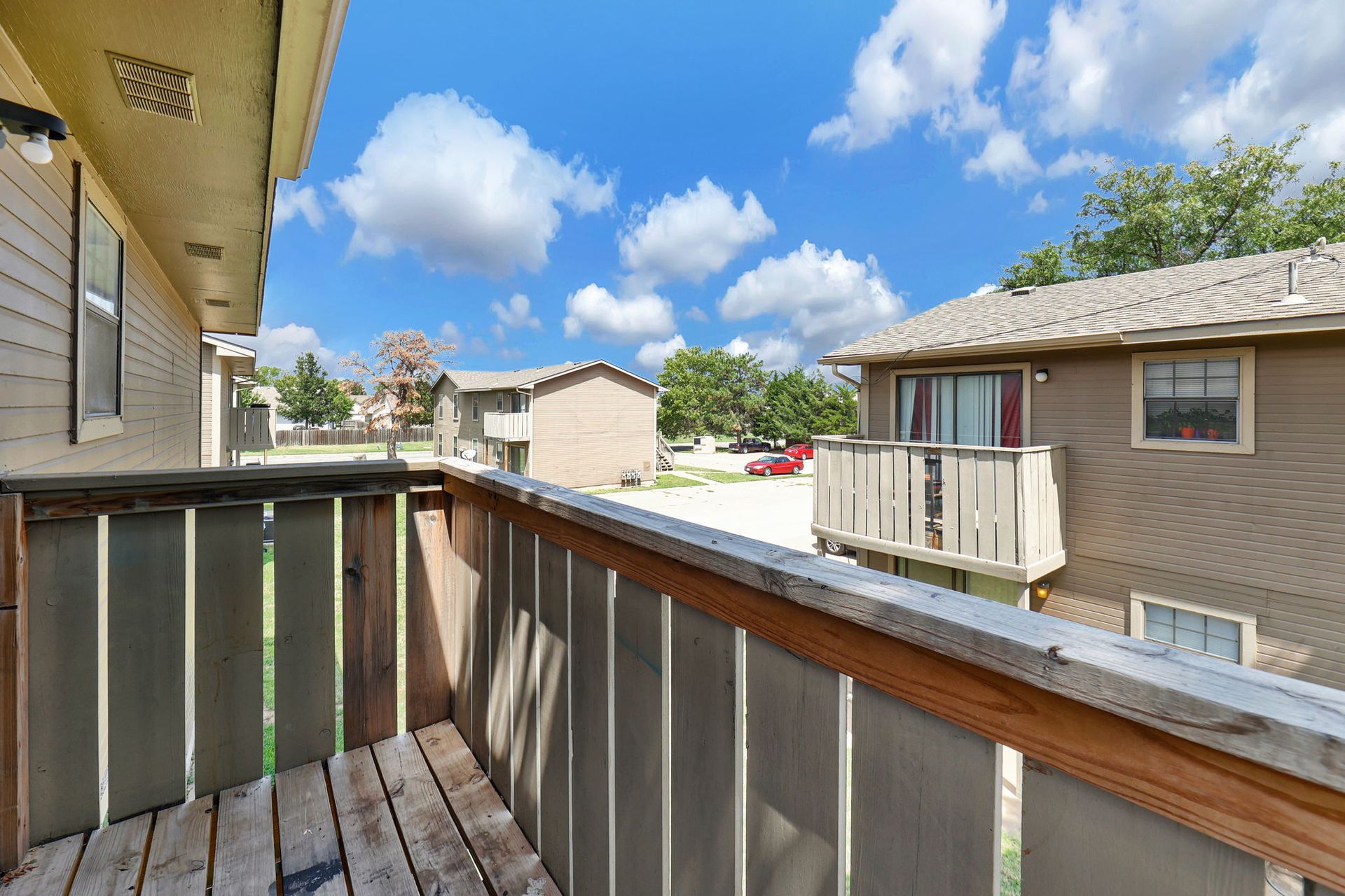 A balcony with a wooden railing and a blue sky in the background.