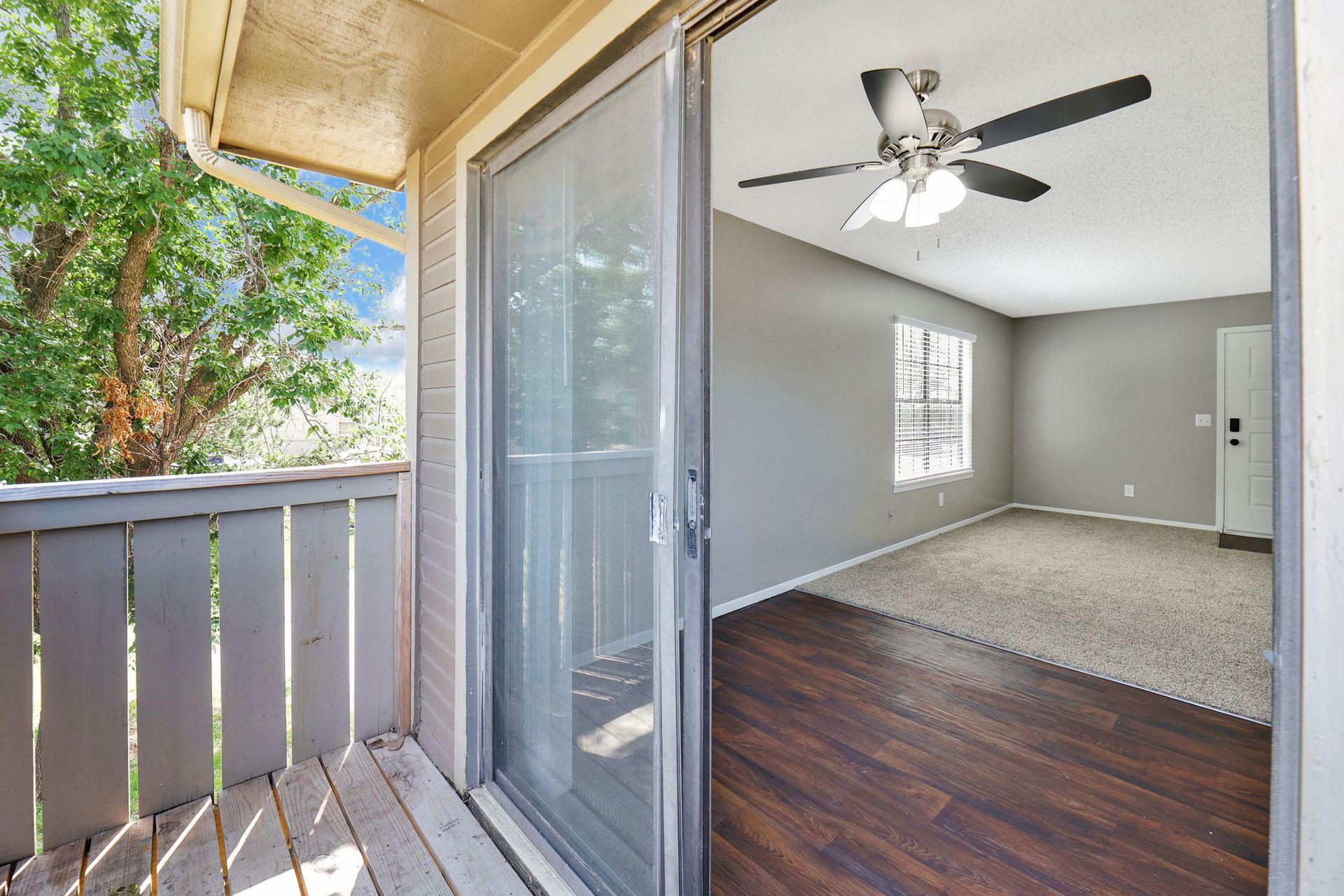 An empty apartment with a sliding glass door and a ceiling fan.