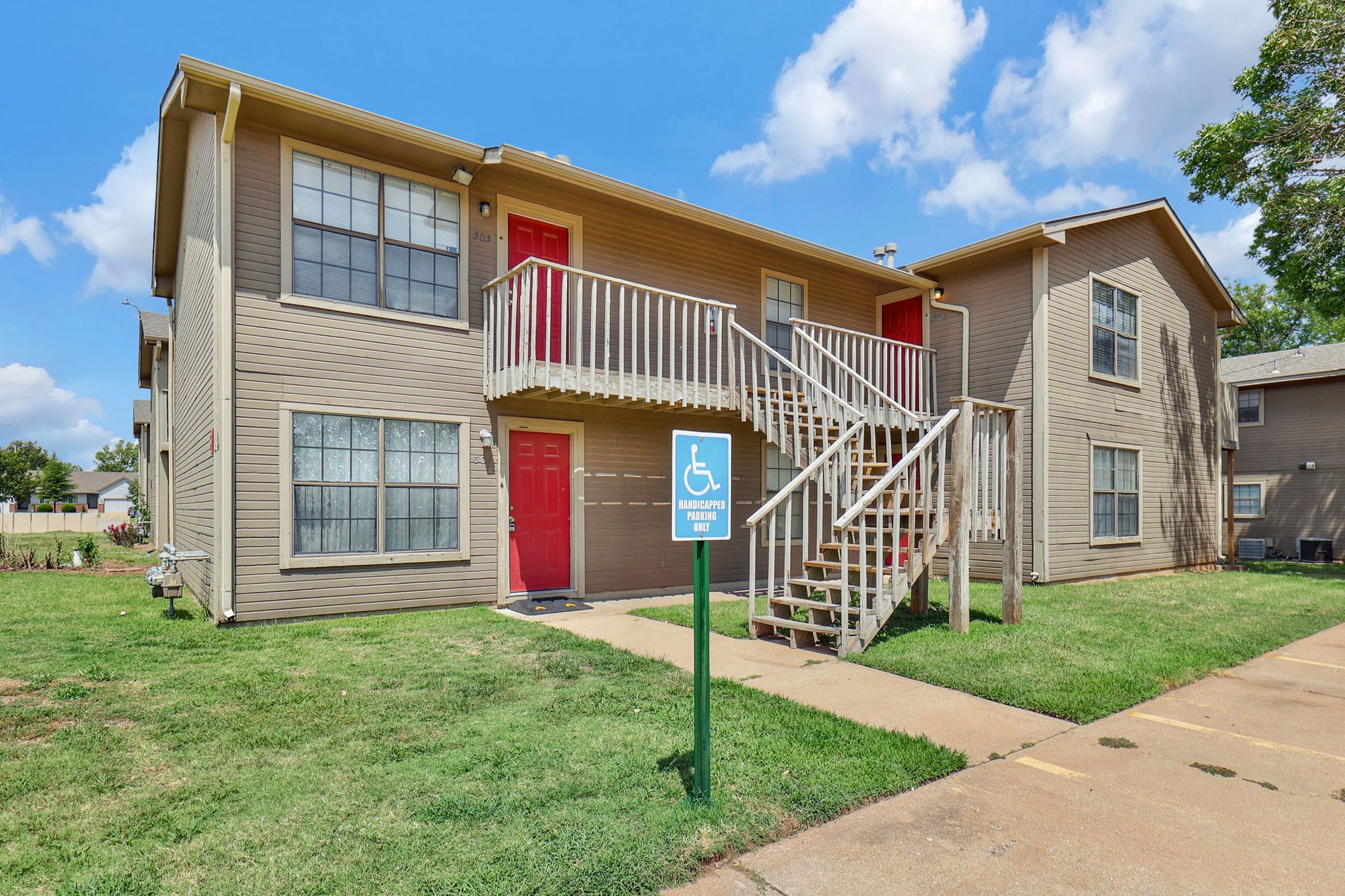 A large apartment building with stairs and a handicapped parking sign in front of it.