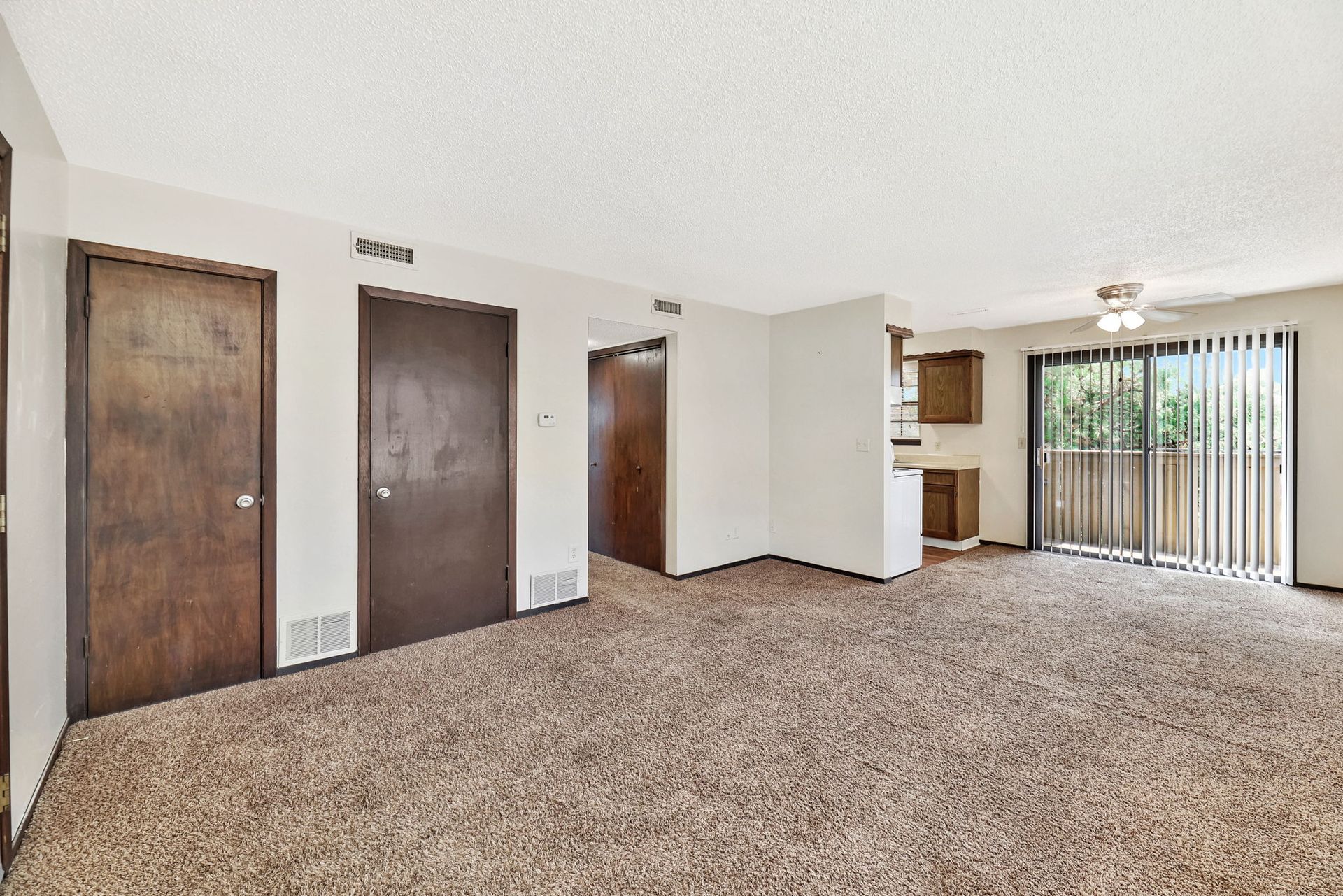 An empty living room with a sliding glass door and a balcony.