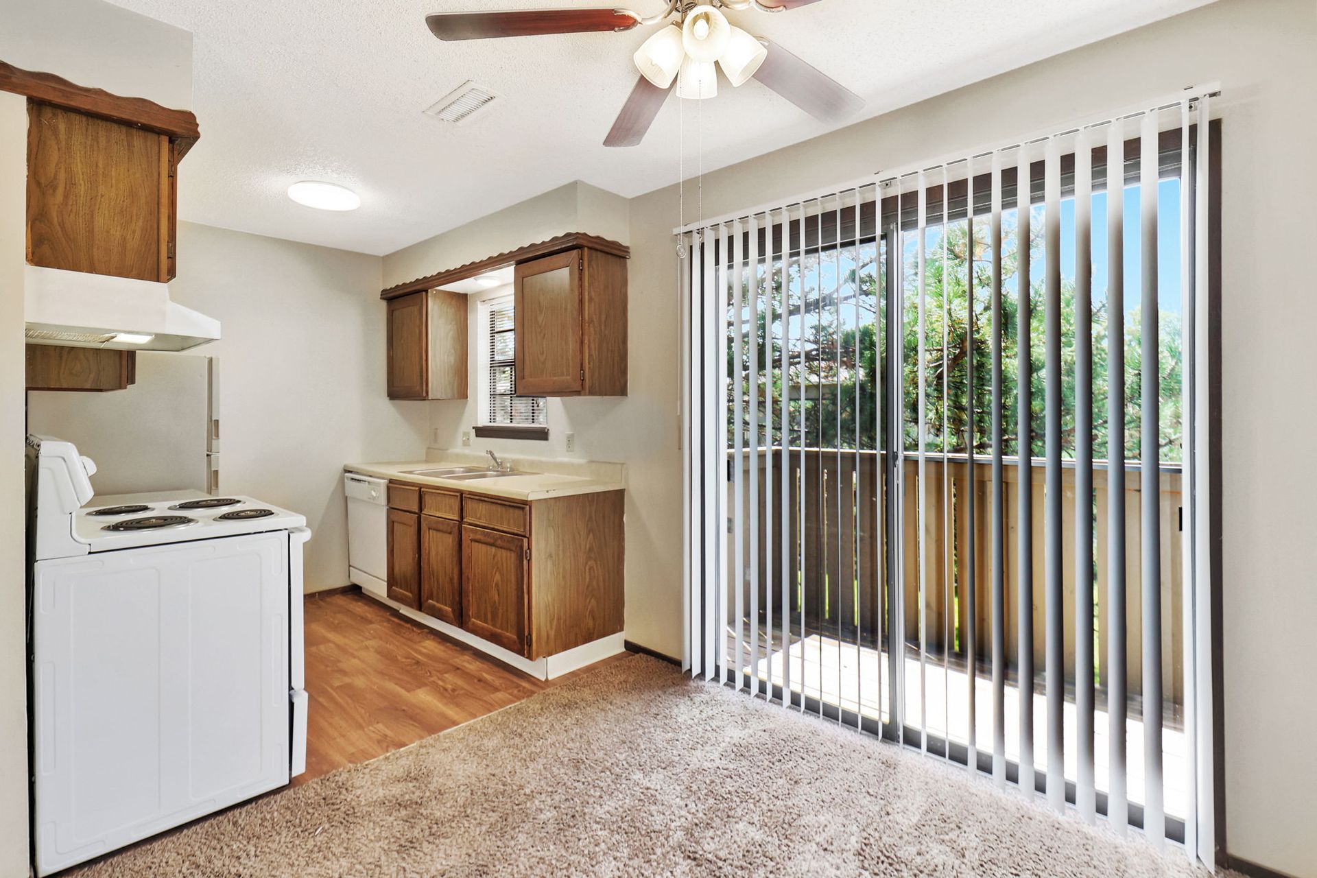 A kitchen with sliding glass doors leading to a balcony and a ceiling fan.