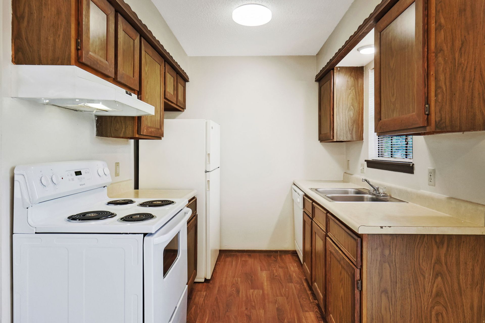 A kitchen with a stove , refrigerator , sink and cabinets.