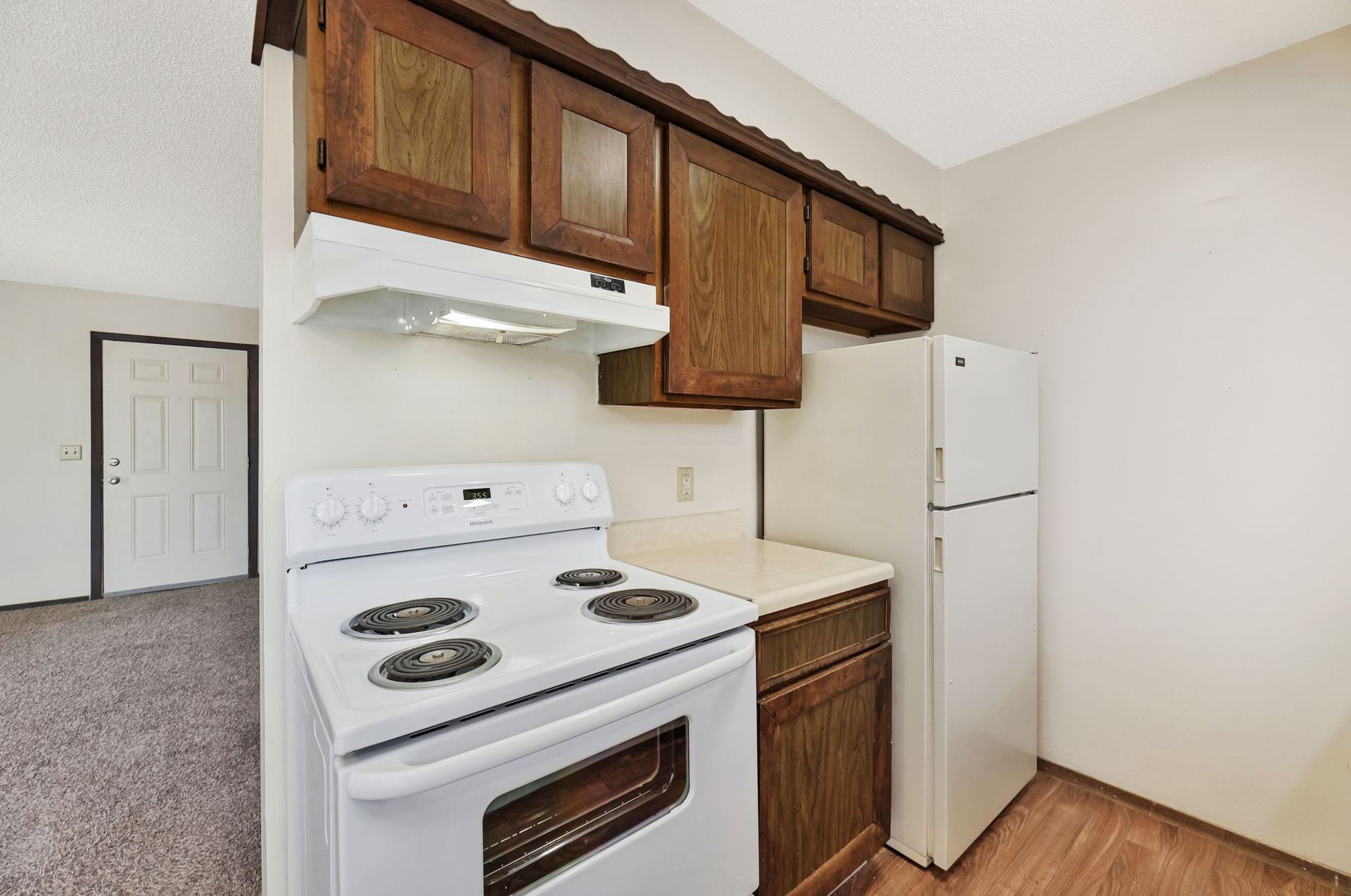 A kitchen with a stove , refrigerator , and cabinets.