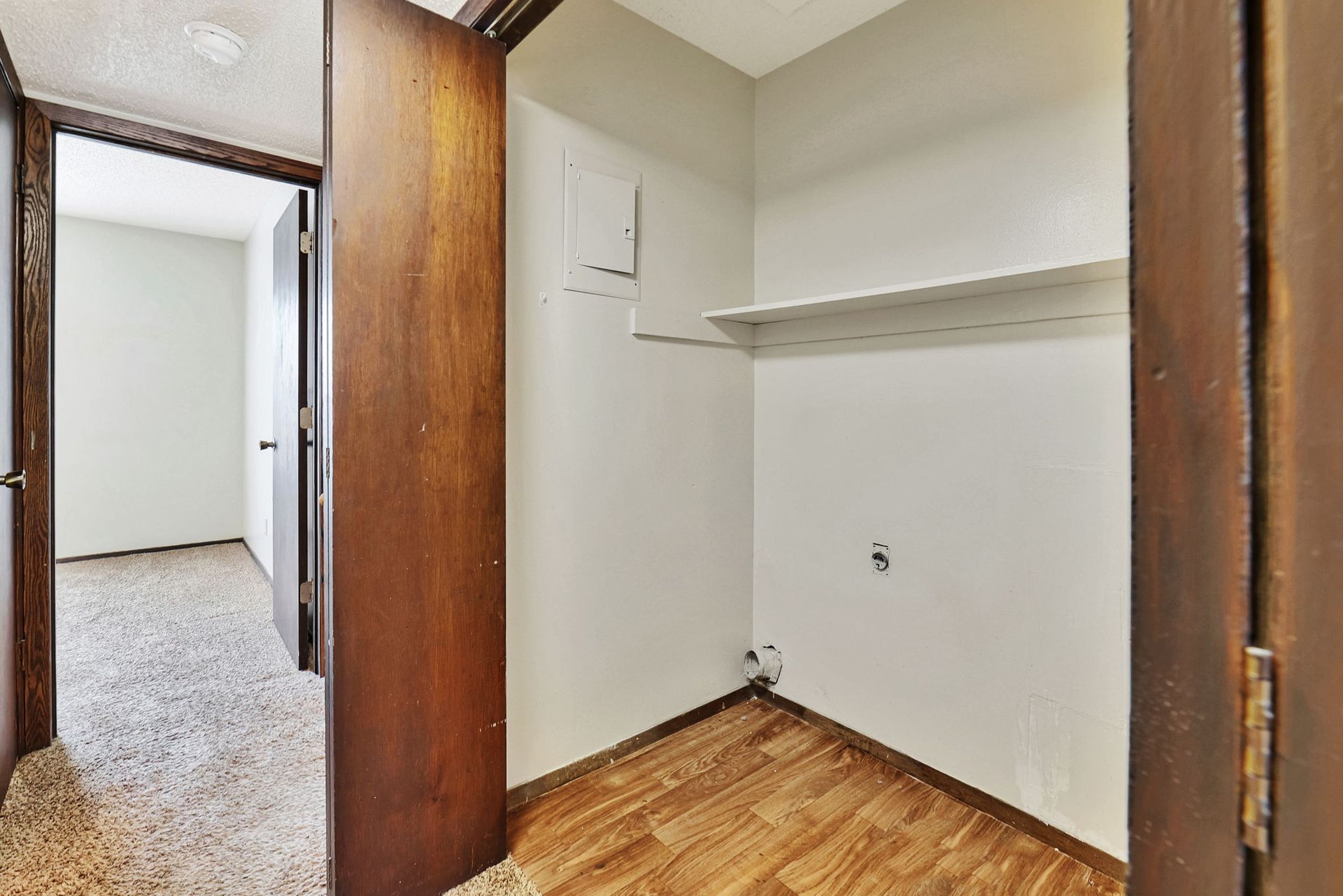 A closet with wooden floors and a wooden door in a house.