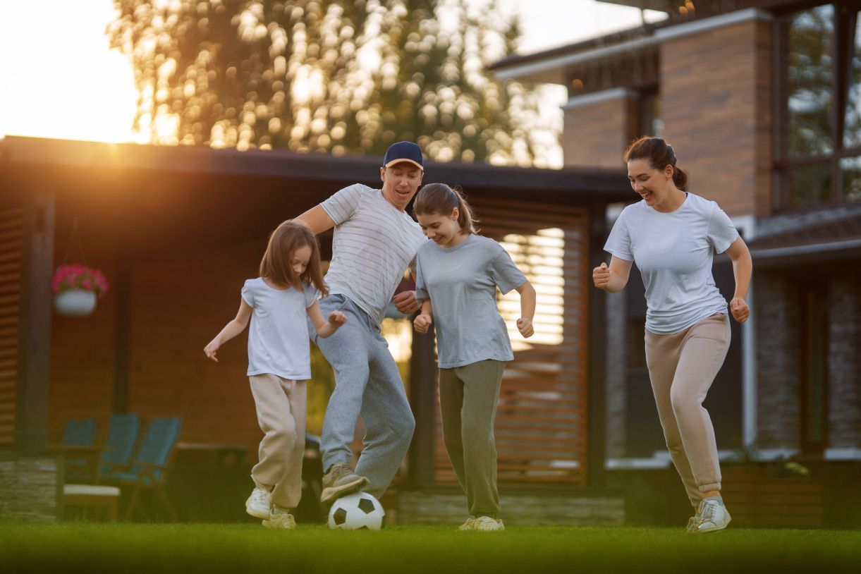 A family is playing soccer in front of their house.