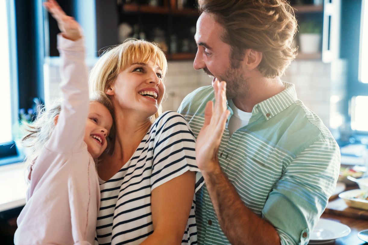 A man and woman are holding a little girl in their arms.