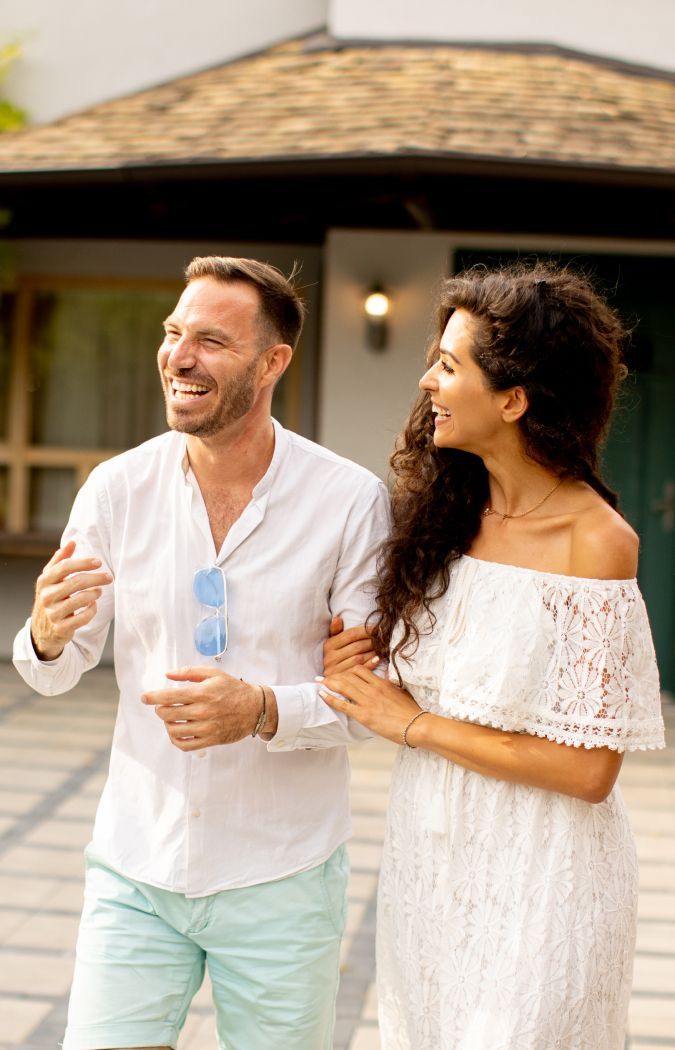 A man and a woman are walking in front of a house.