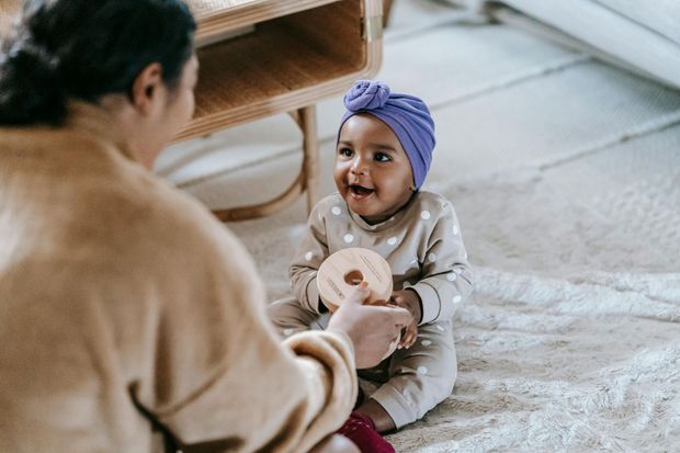 A woman is feeding a baby with a bottle while sitting on the floor.