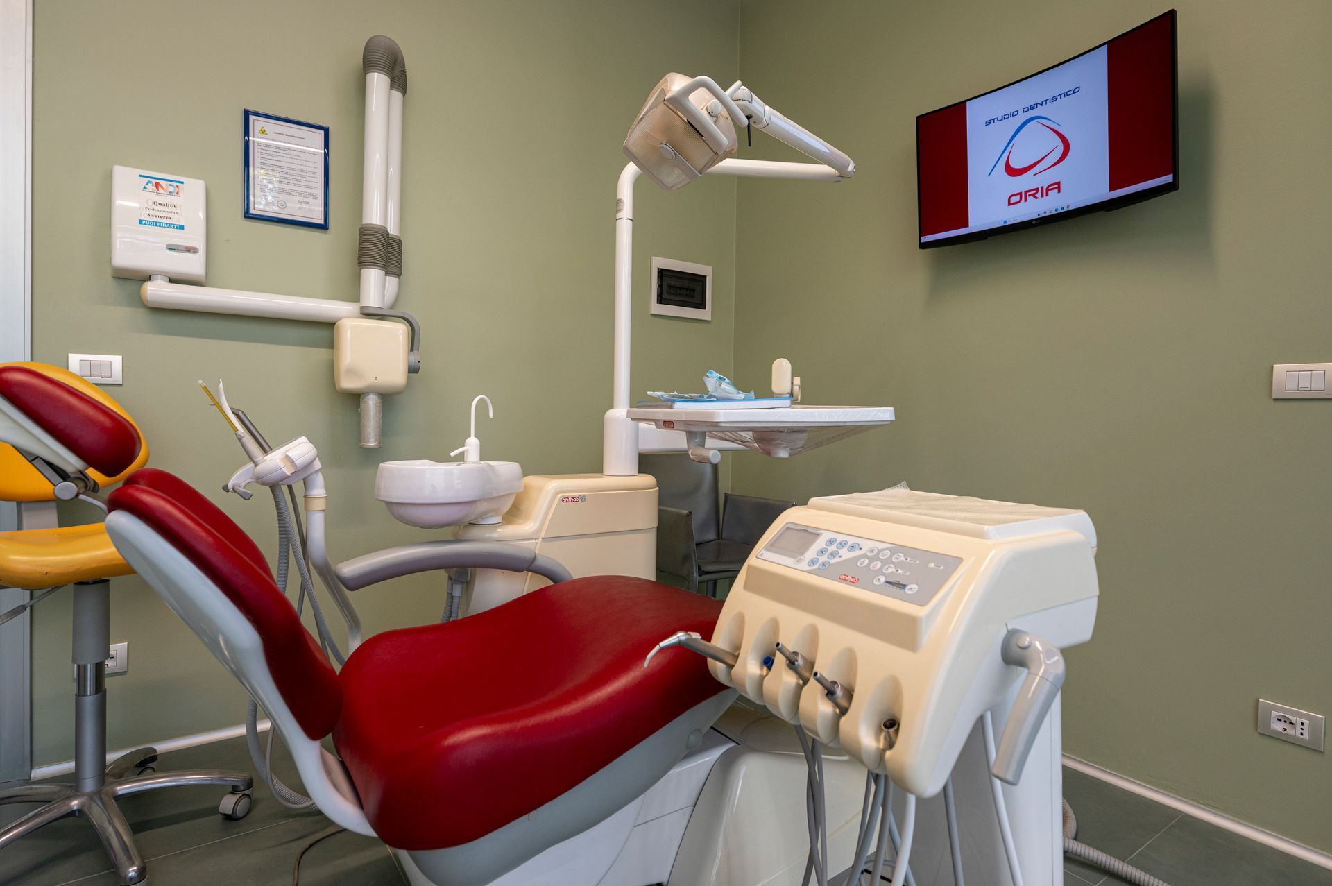 Sala visita dello studio dentistico con poltrona odontoiatrica rossa e attrezzatura.