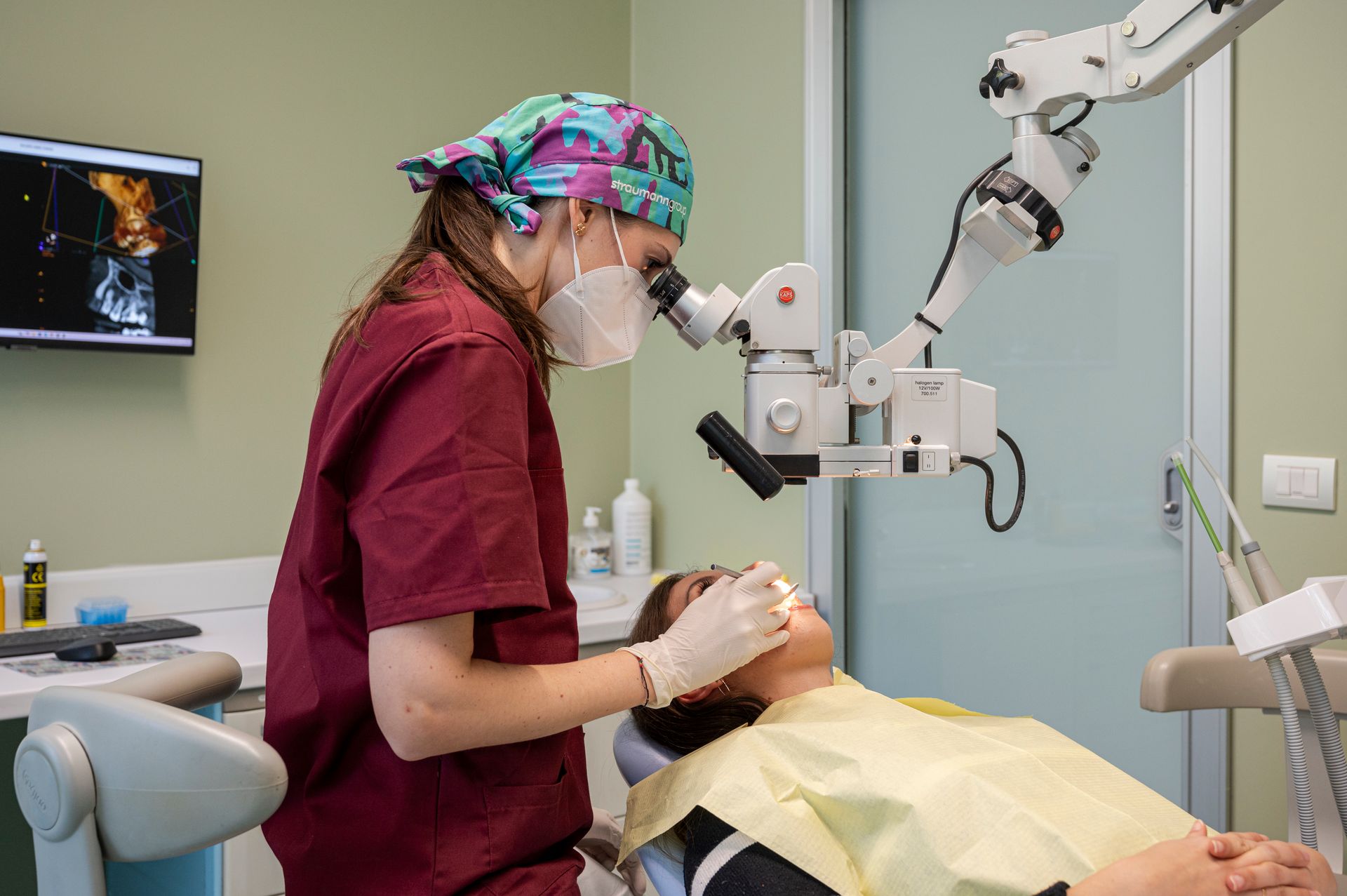 Un dentista esamina la bocca di un paziente al microscopio. Il paziente è sdraiato.