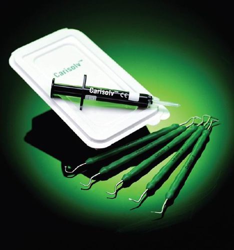 Strumenti odontoiatrici: siringa, vassoio e diversi stuzzicadenti su sfondo verde.