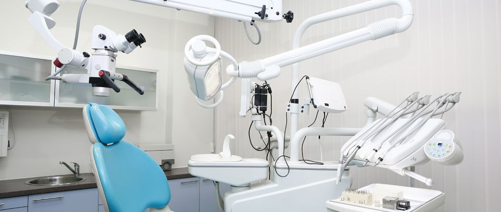 Uno studio dentistico con poltrona, strumenti e attrezzature, tutto in bianco e azzurro.