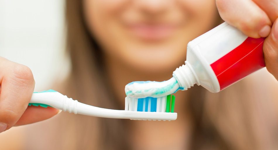 Persona che spreme il dentifricio sullo spazzolino.
