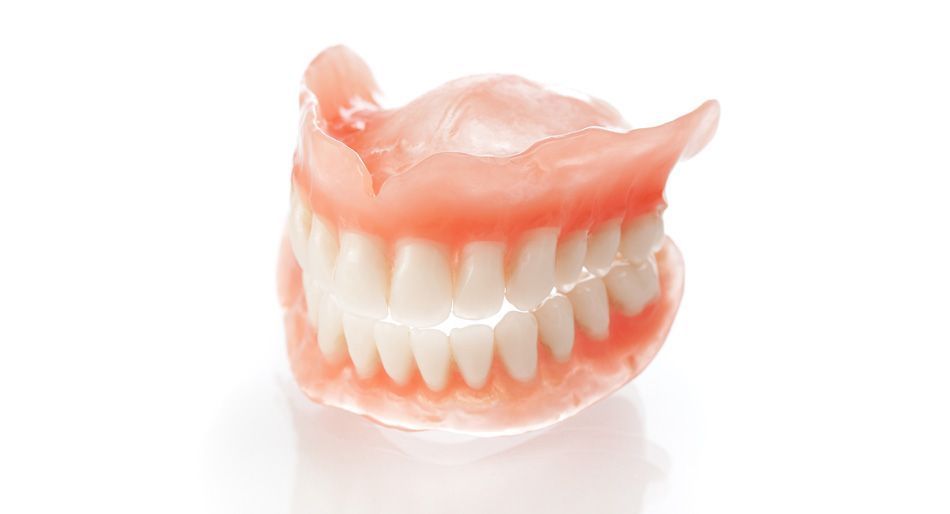 Una serie di dentiere con denti bianchi e gengive rosa, su uno sfondo bianco.