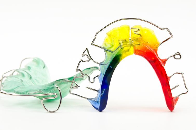 Un apparecchio ortodontico colorato, principalmente rosso, giallo, blu e verde, con struttura in filo metallico.