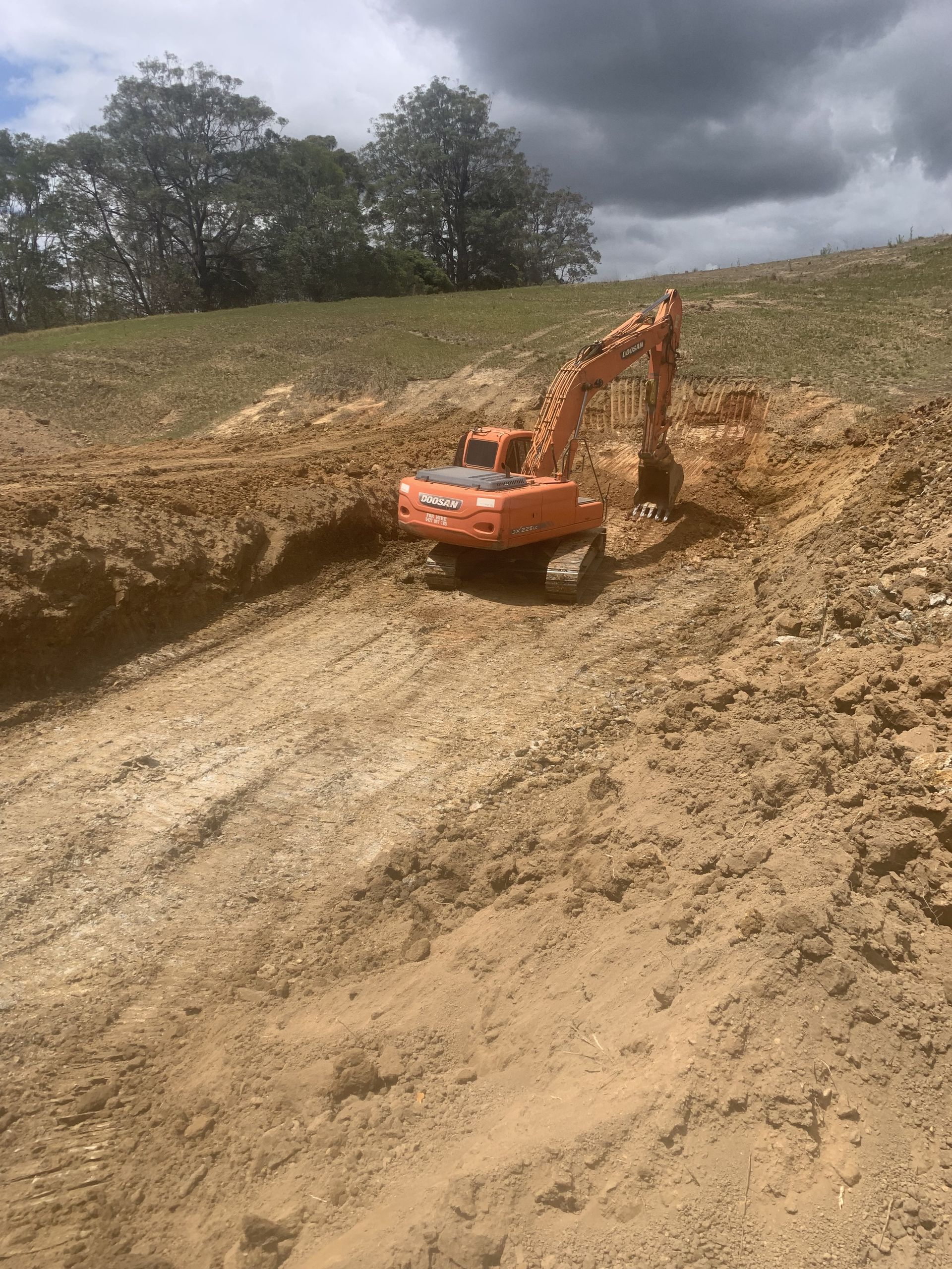 A large orange excavator is driving down a dirt road — Gears Excavation In Cedar Pocket, QLD