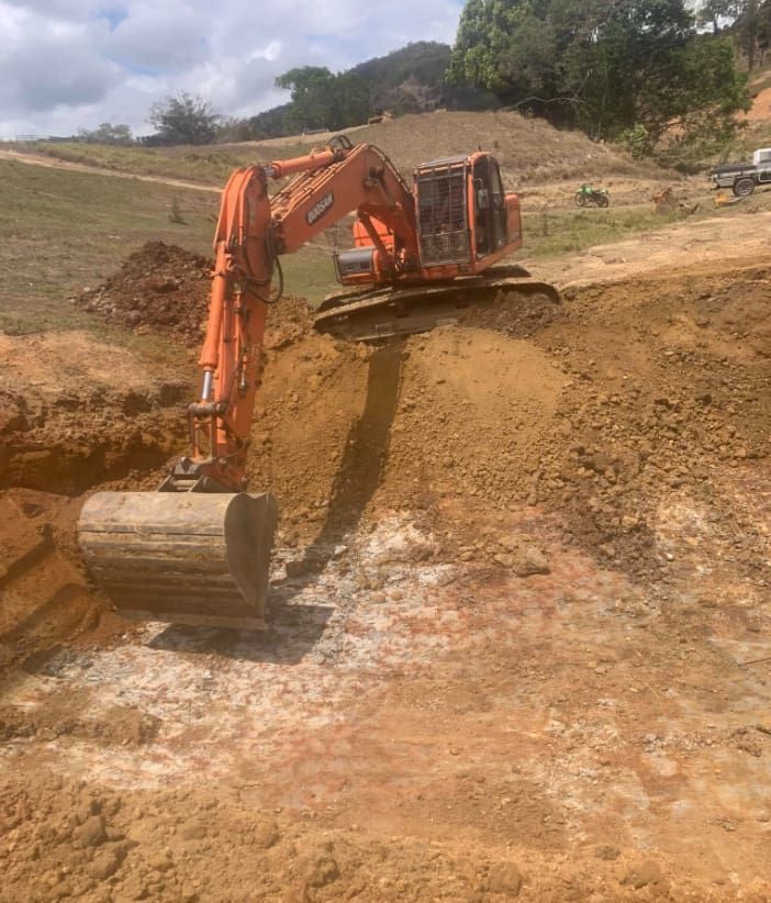 A Large Orange Excavator is Digging a Hole in the Dirt — Gears Excavation In Cedar Pocket, QLD