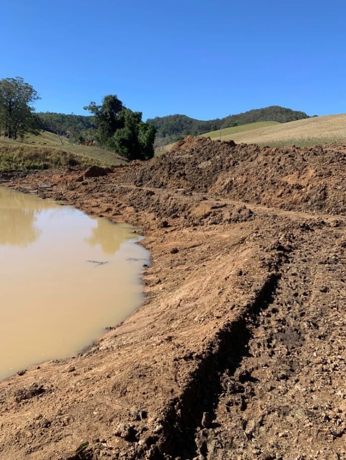 A Muddy Field With a Small Pond in the Middle of It — Gears Excavation In Cedar Pocket, QLD