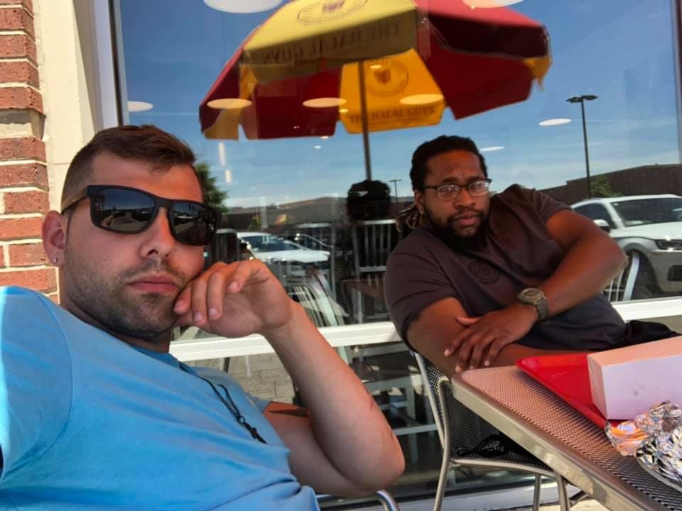 Two men are sitting at a table with Manny Hudson