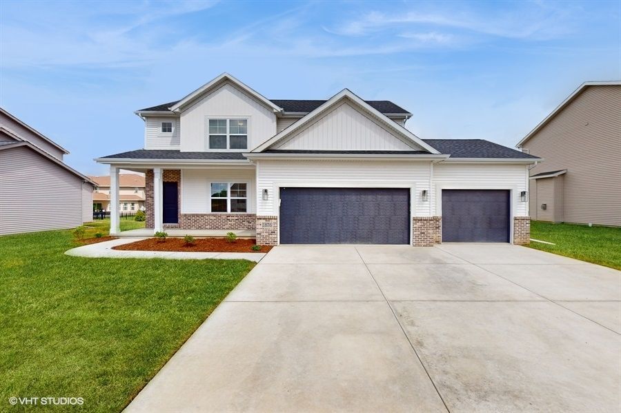 A large white house with two garages and a concrete driveway.