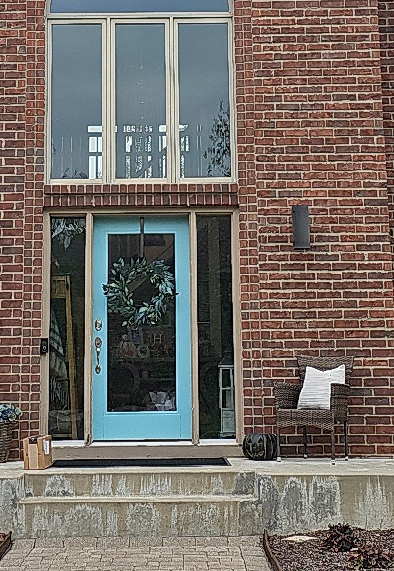 A Brick House with A Blue Door and A Chair in Front of It — Carver, MN — TJ Exteriors Inc.