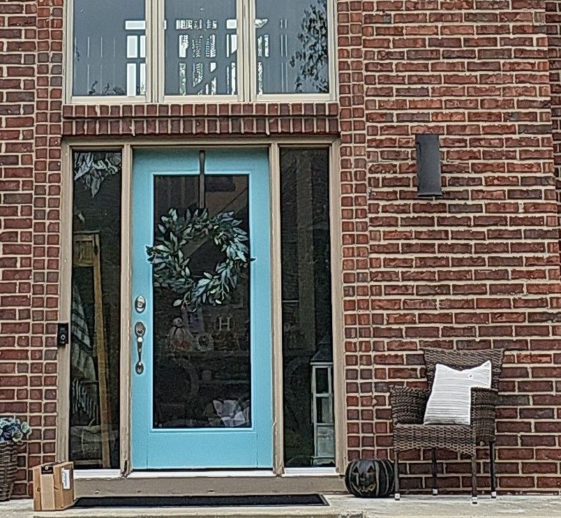 A Brick House with A Blue Door and A Chair in Front of It — Carver, MN — TJ Exteriors Inc.