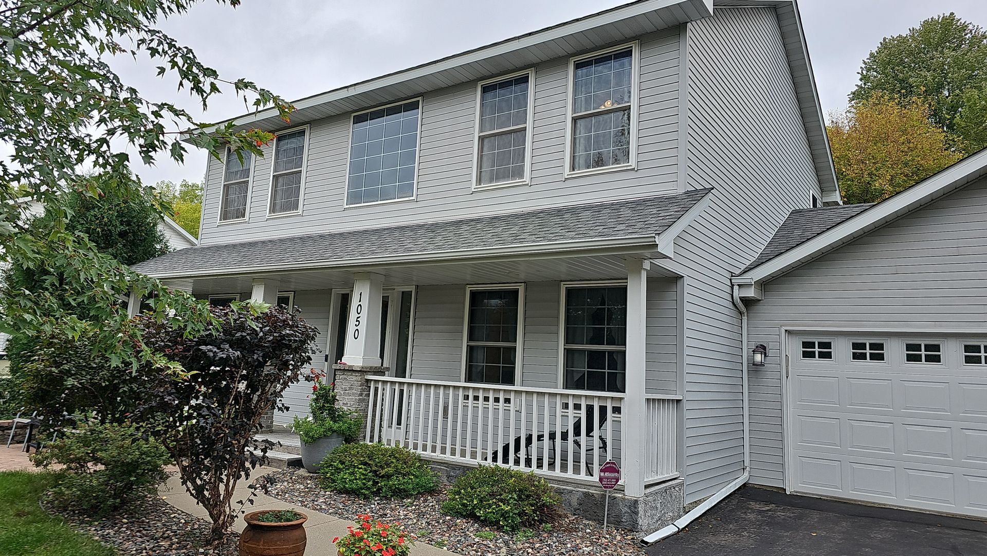 A white house with a large porch and a garage.