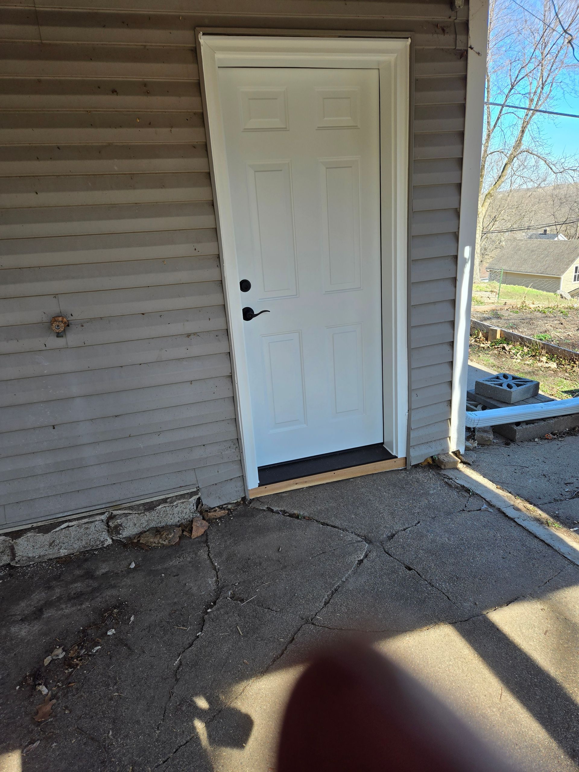 A white door is on the side of a house.