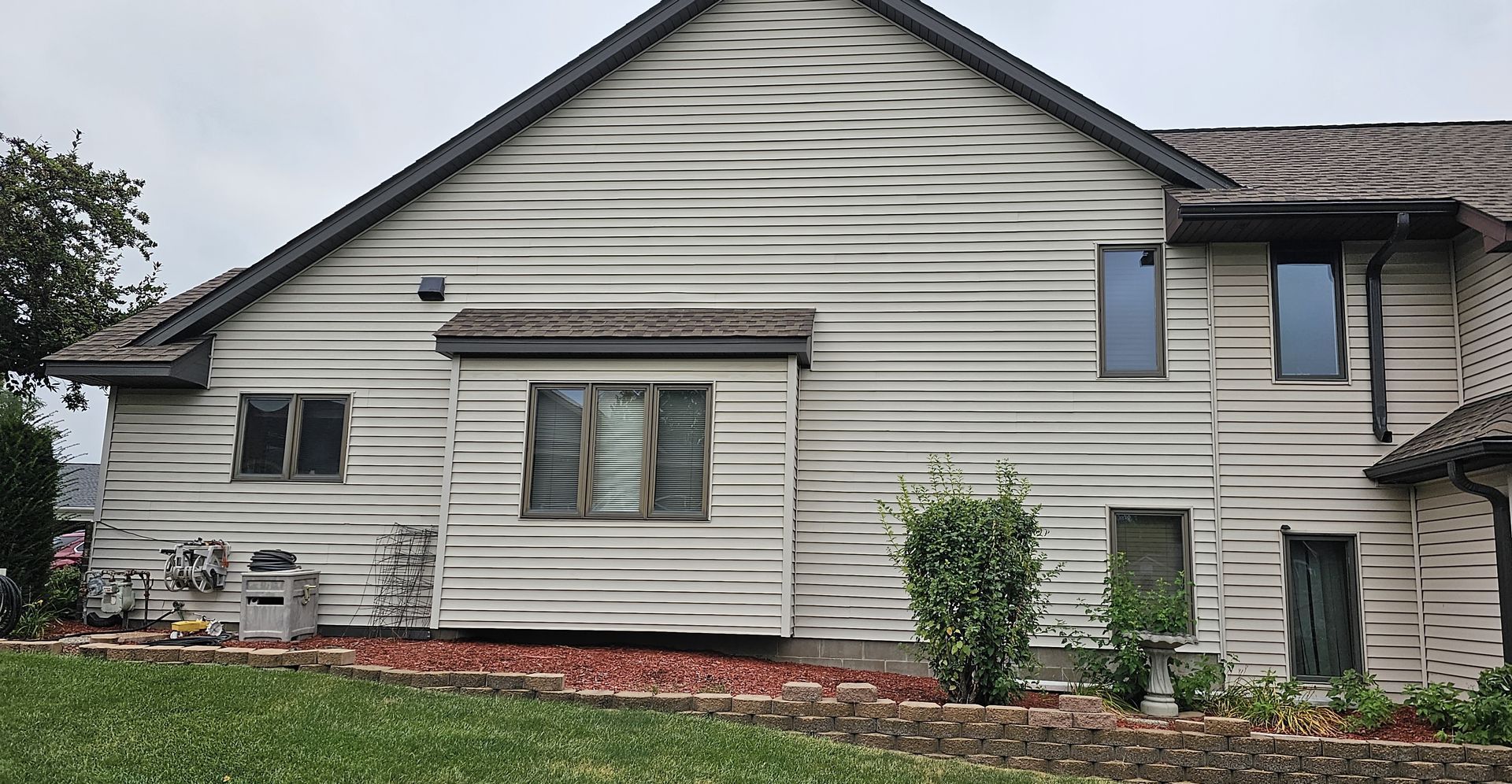 The back of a house with a lot of windows and a roof.