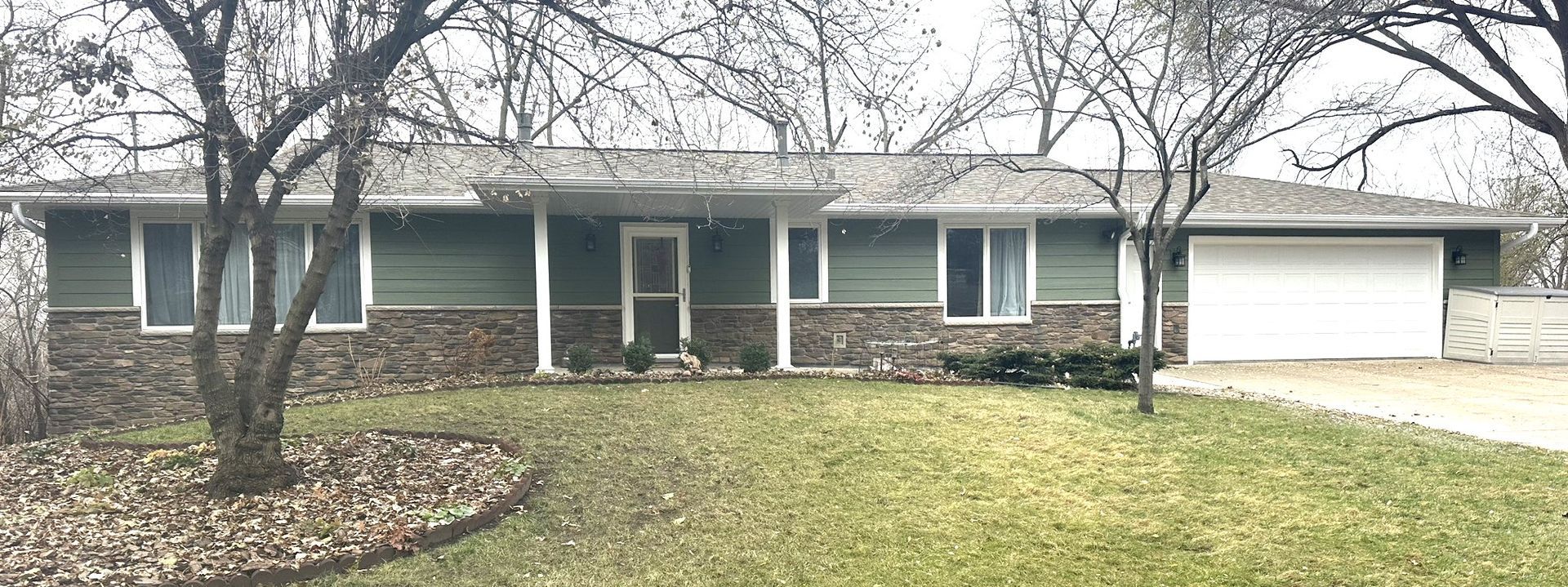 A house with a green siding and a white garage door