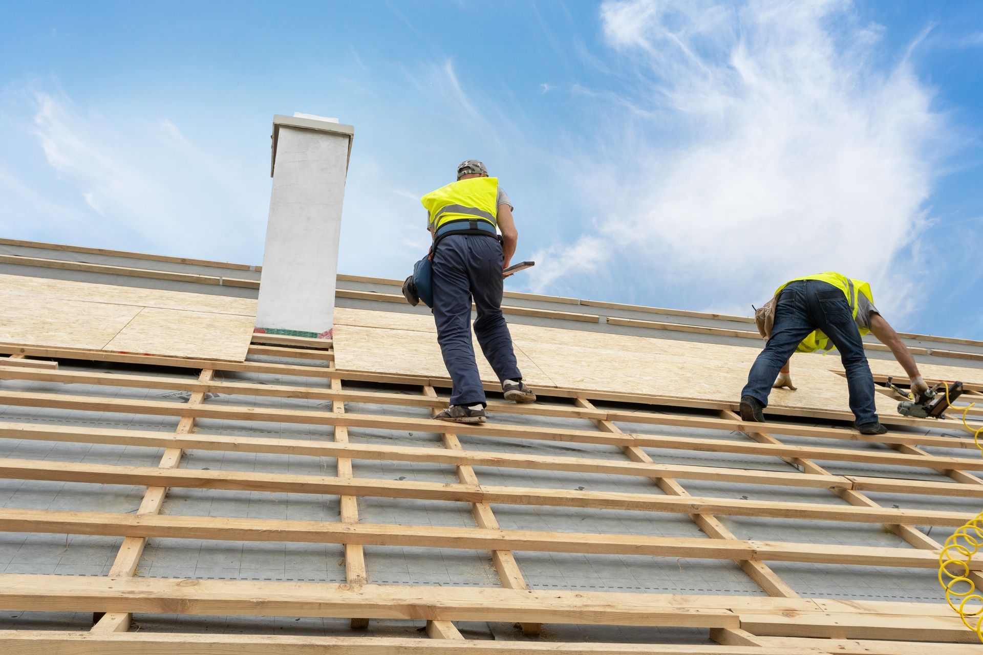 Roofing professionals installing new plywood decking during a residential roof replacement project. Roofing professionals installing new plywood decking during a residential roof replacement project.