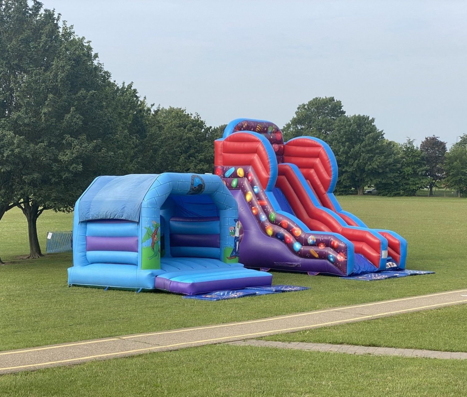 blue bouncy castle and multi colour slide on a school field. Anchored securely  on a calm day. 