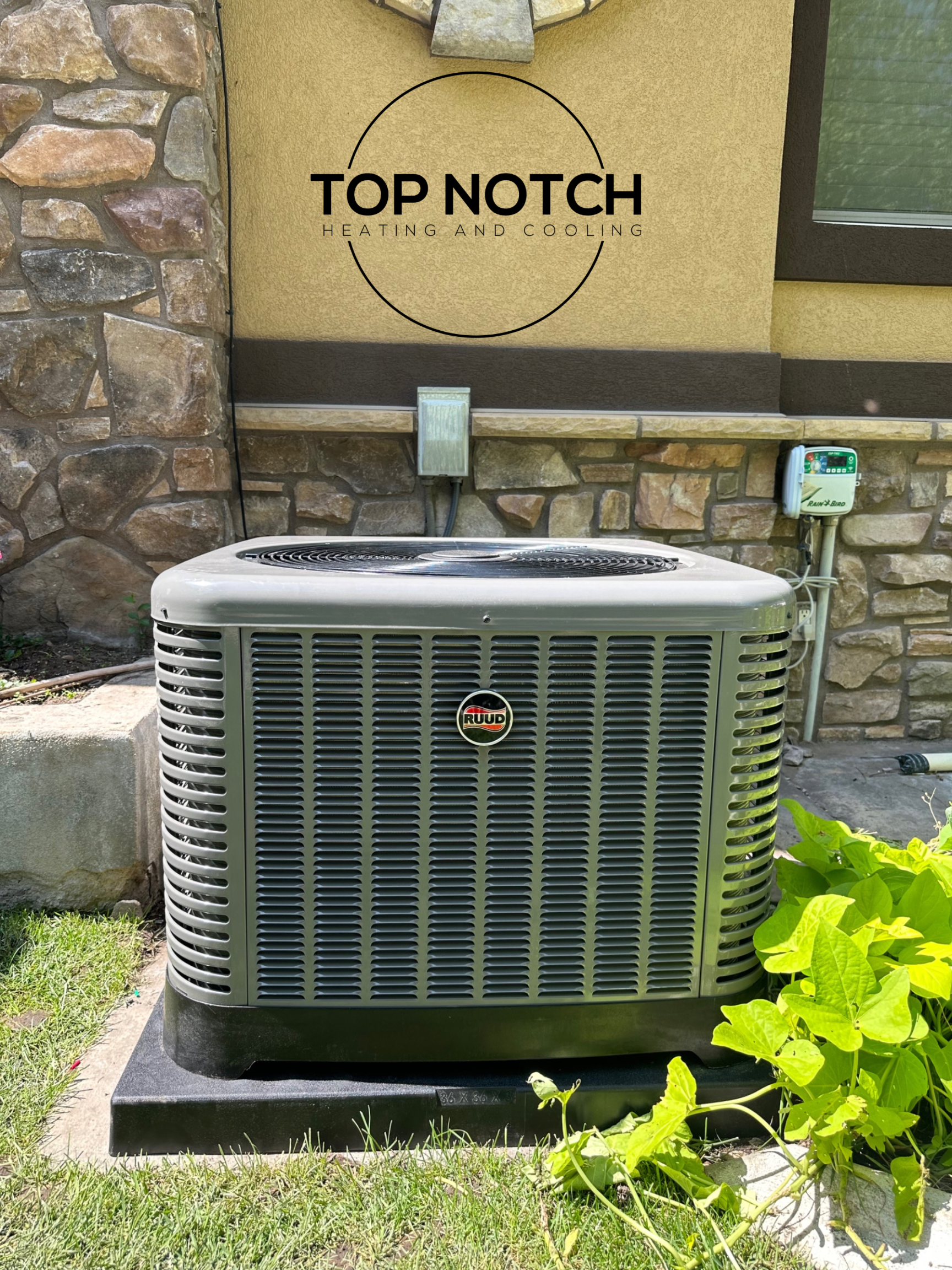 A large air conditioner is sitting in front of a stone building.