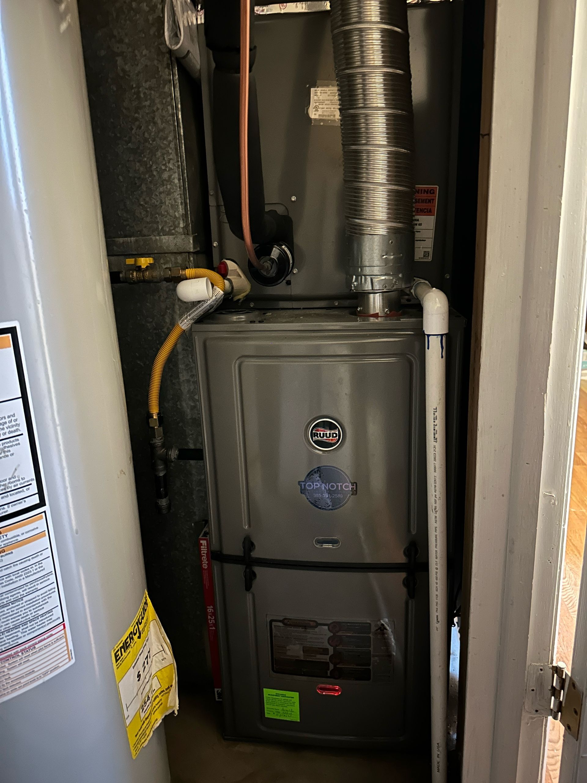 An air conditioner is sitting in a closet next to a water heater.