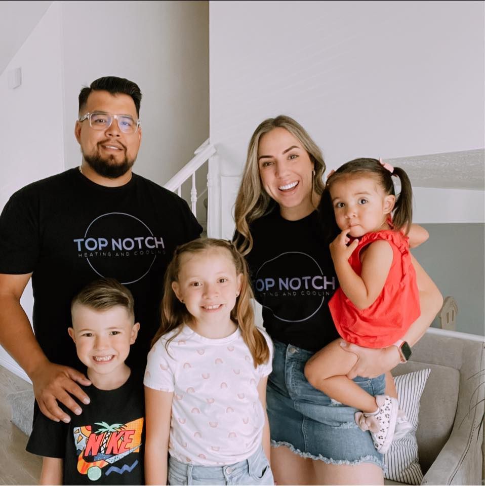 A group of people are posing for a picture and one of their shirts says top notch