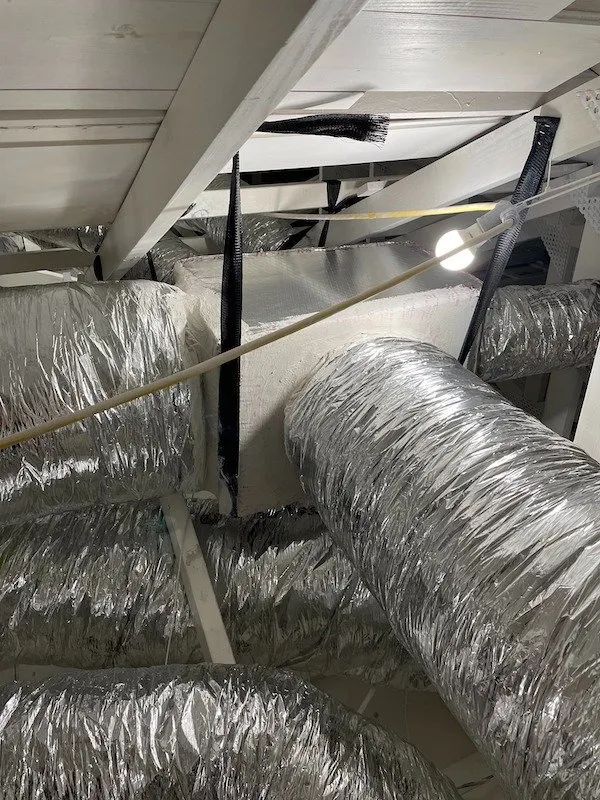 A bunch of ducts are hanging from the ceiling in a room.