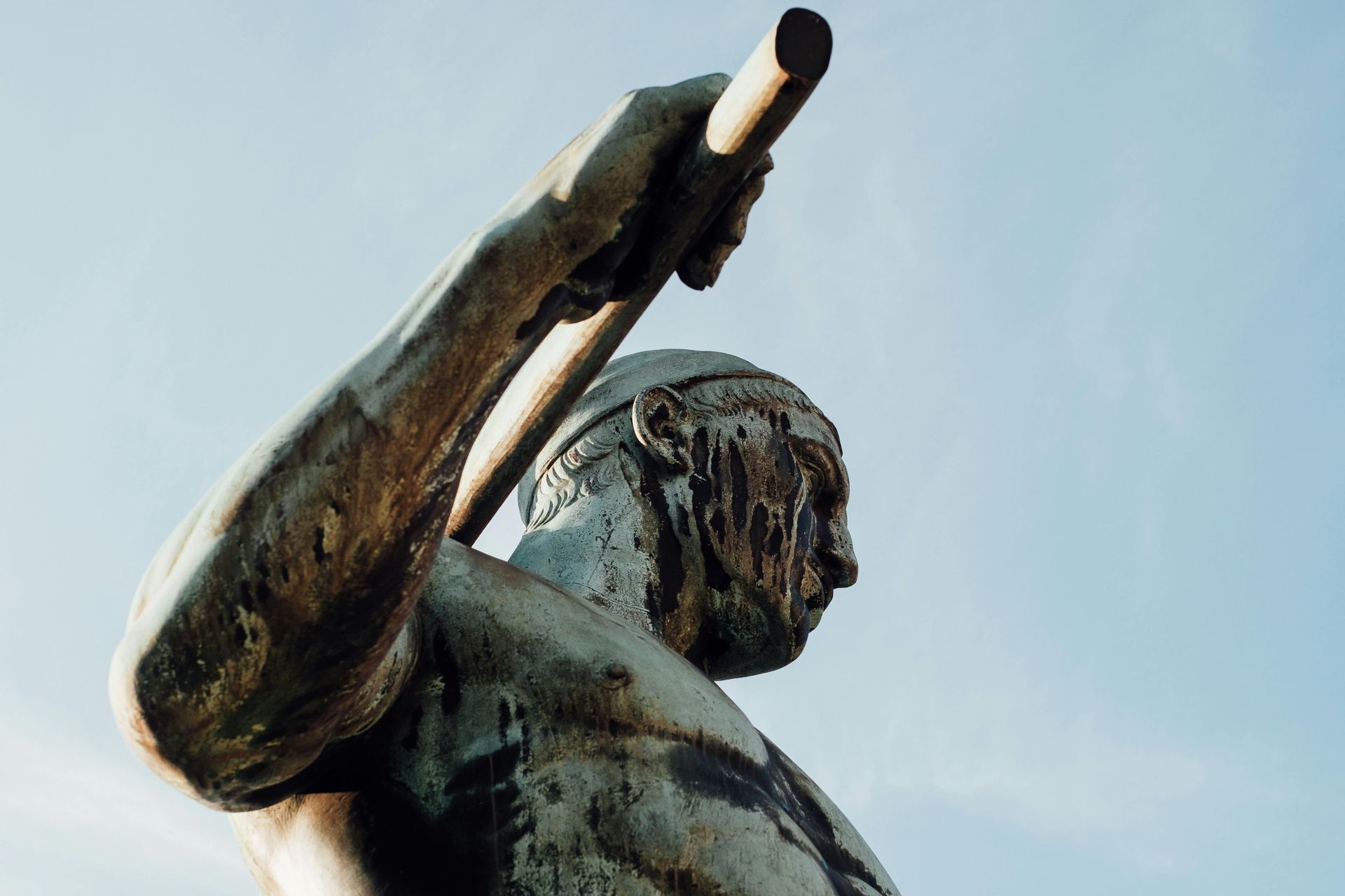 A statue of a man holding a pipe against a blue sky.