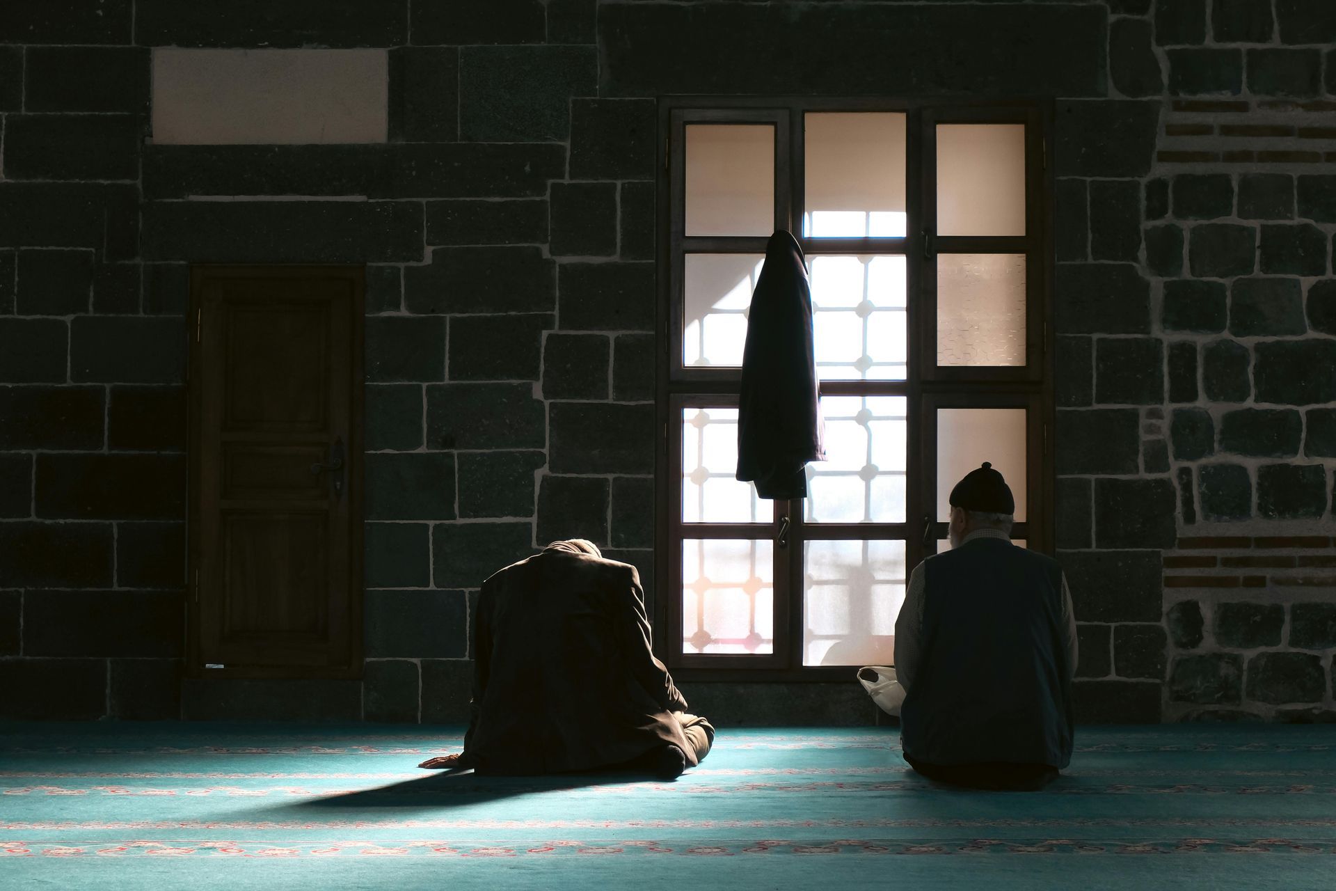 A man is sitting in front of a window in a dark room