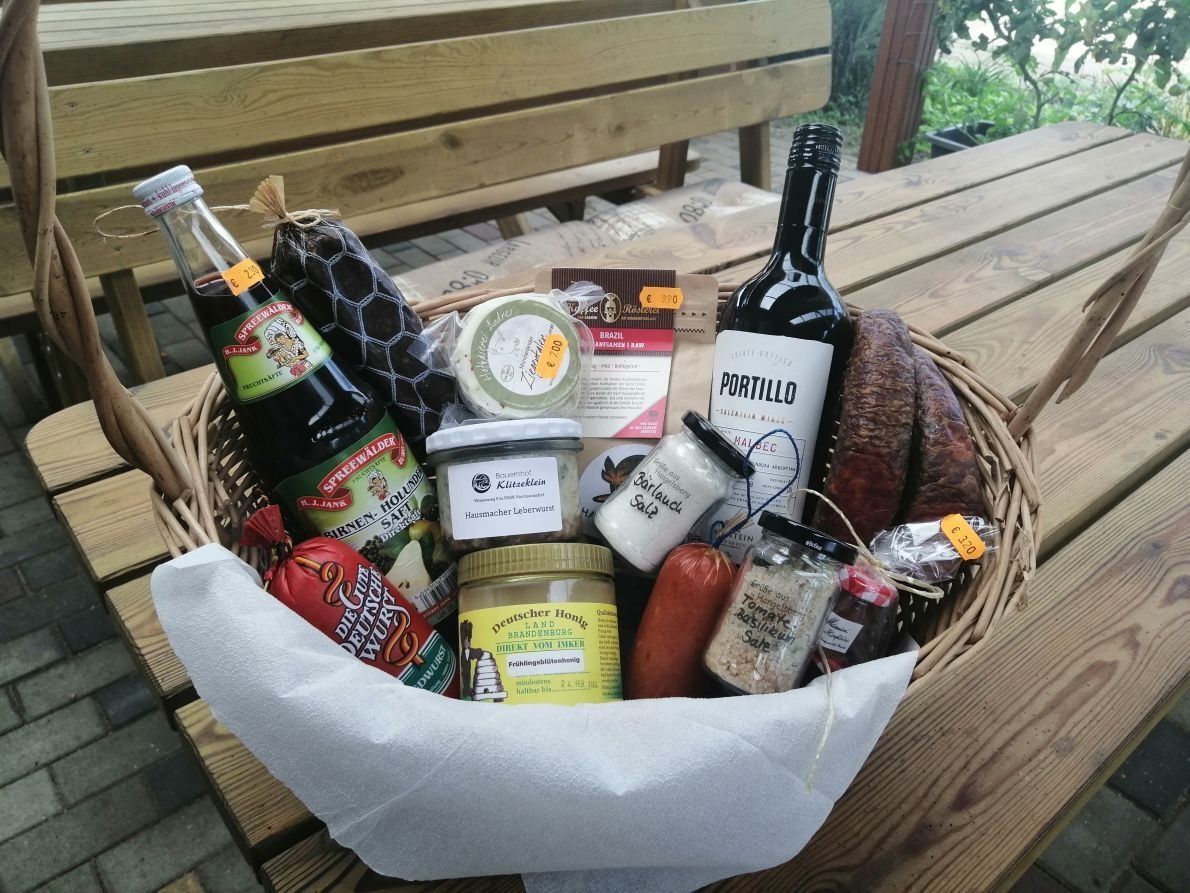 Ein Geschenkkorb voller Lebensmittel und eine Flasche Wein auf einem Holztisch.