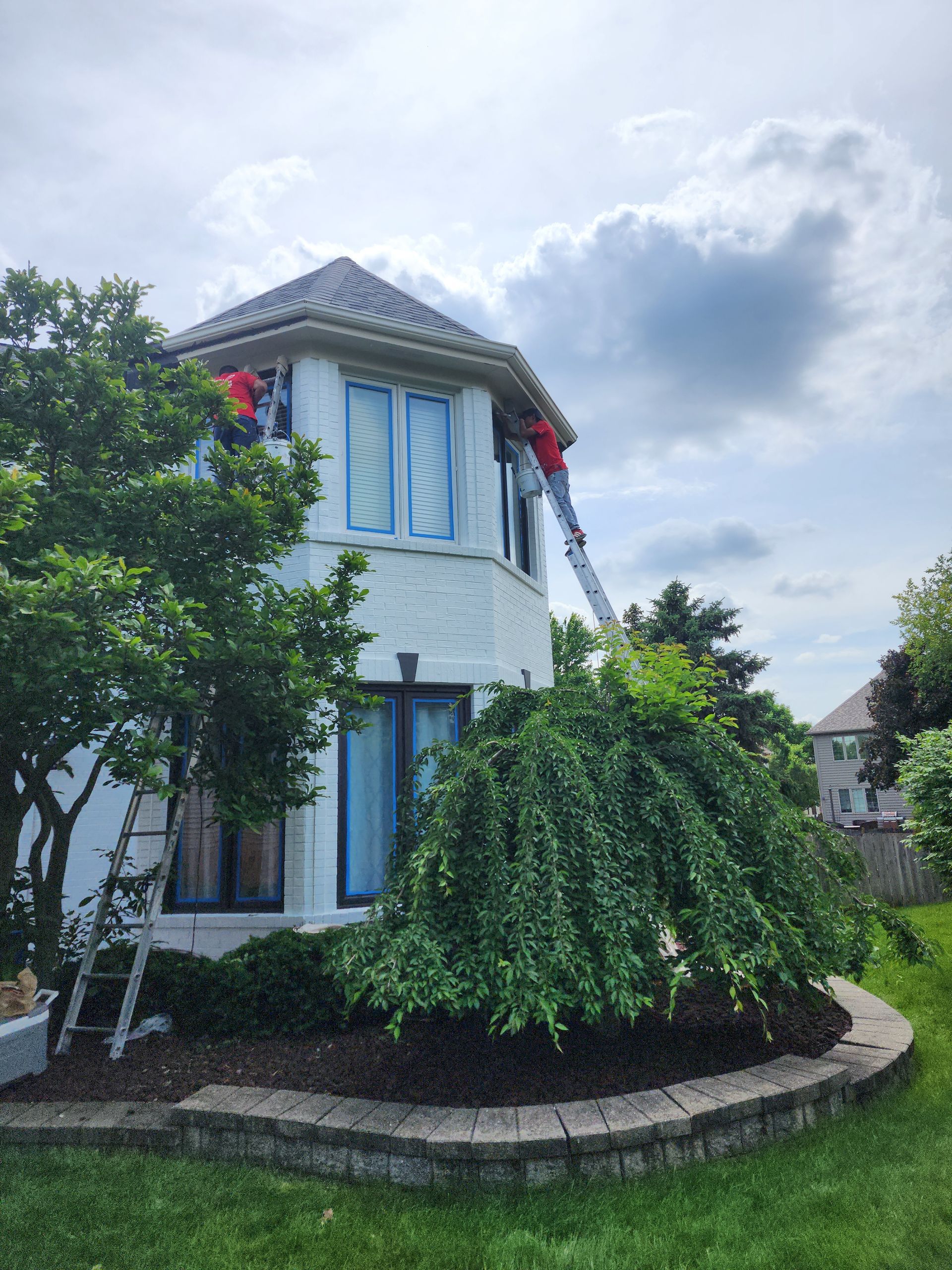 A man is standing on a ladder on the roof of a house.