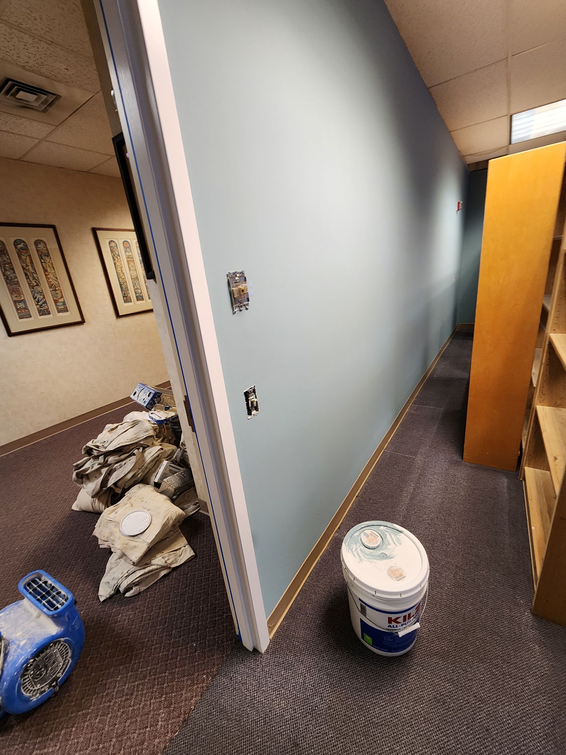 A bucket of paint is sitting on the floor in a room.