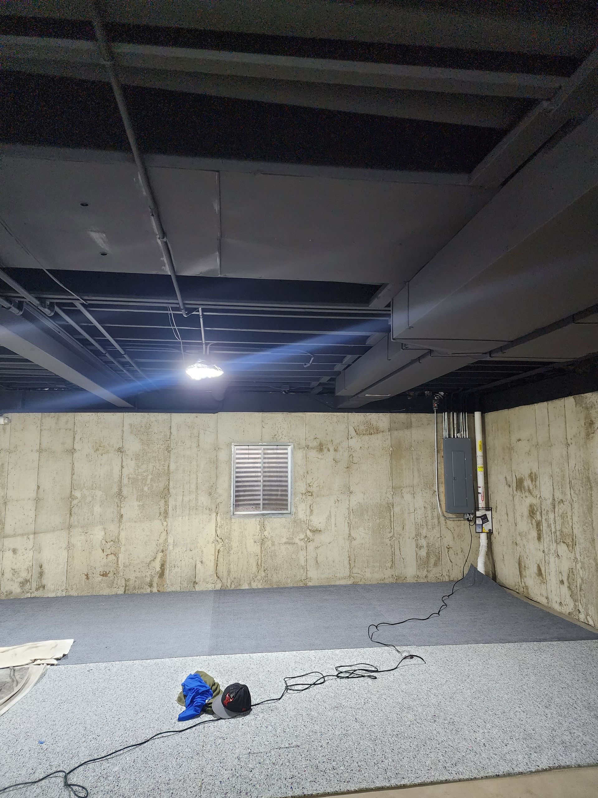 An empty basement with a carpeted floor and a window.