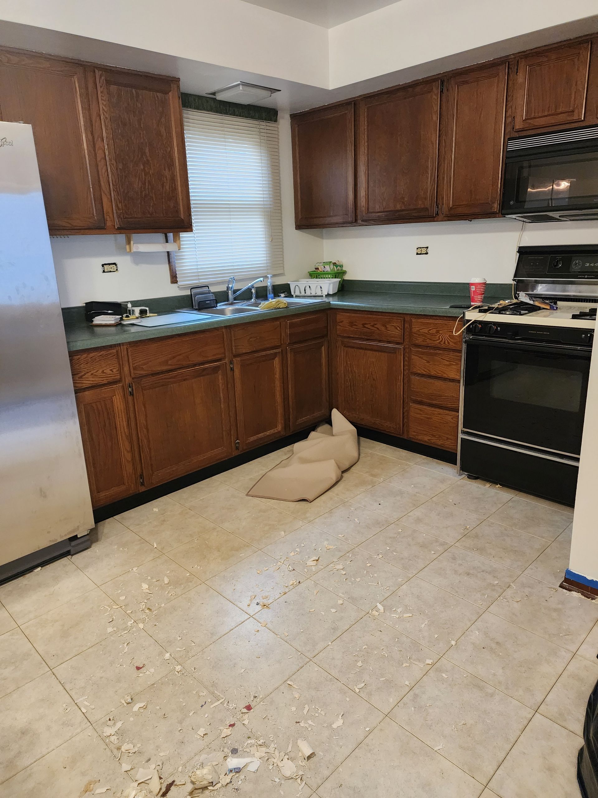 A kitchen with wooden cabinets , a stove , a refrigerator and a microwave.