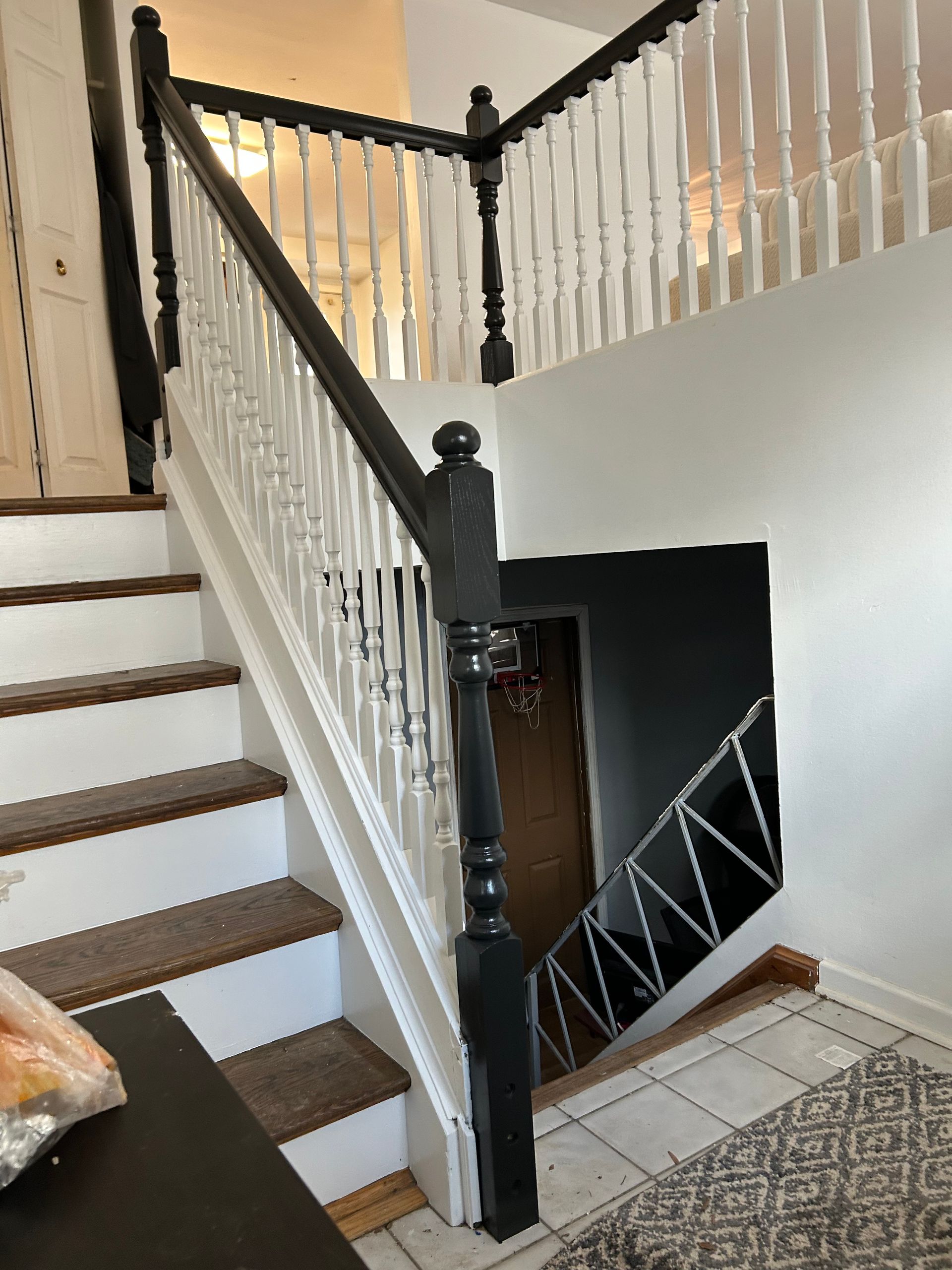 Staircase with white balusters, black handrails and newel posts. Stairs are carpeted.